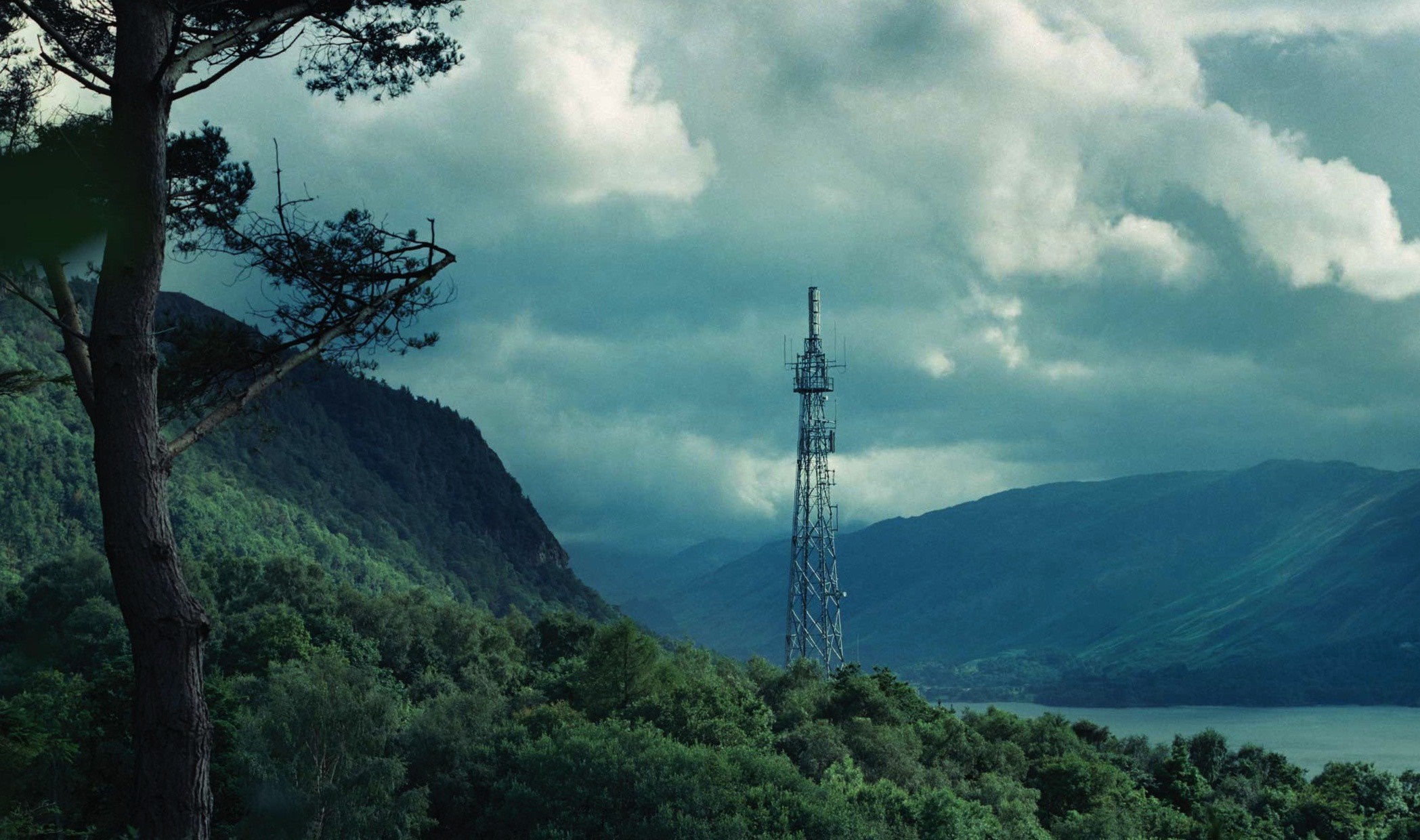 Cell tower on a forested mountain overlooking a lake HD Wallpaper