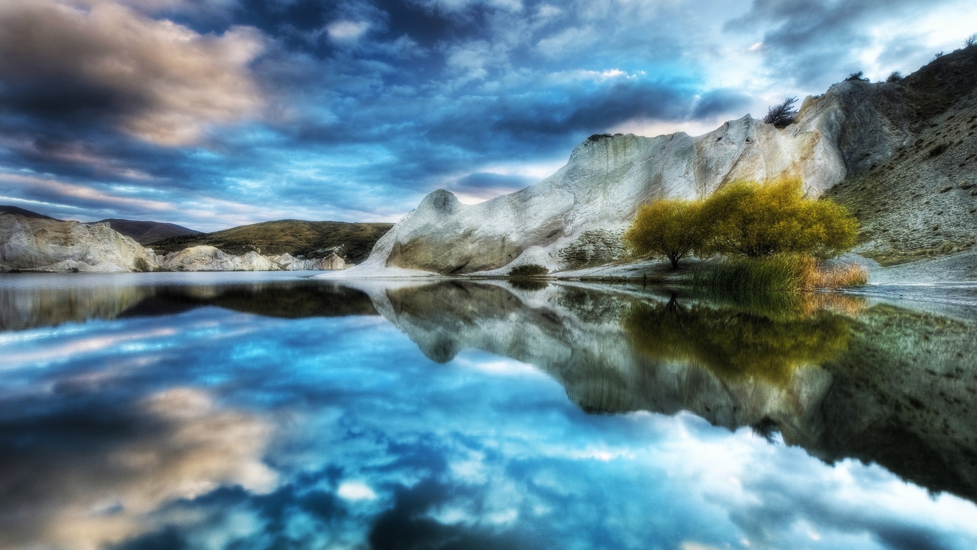 Lake reflecting dramatic clouds and white rock formations HD Wallpaper