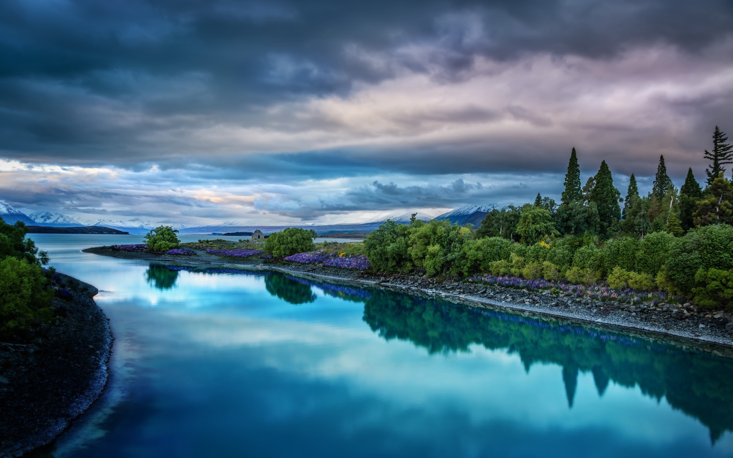 Calm lake reflecting trees and mountains under cloudy sky HD Wallpaper