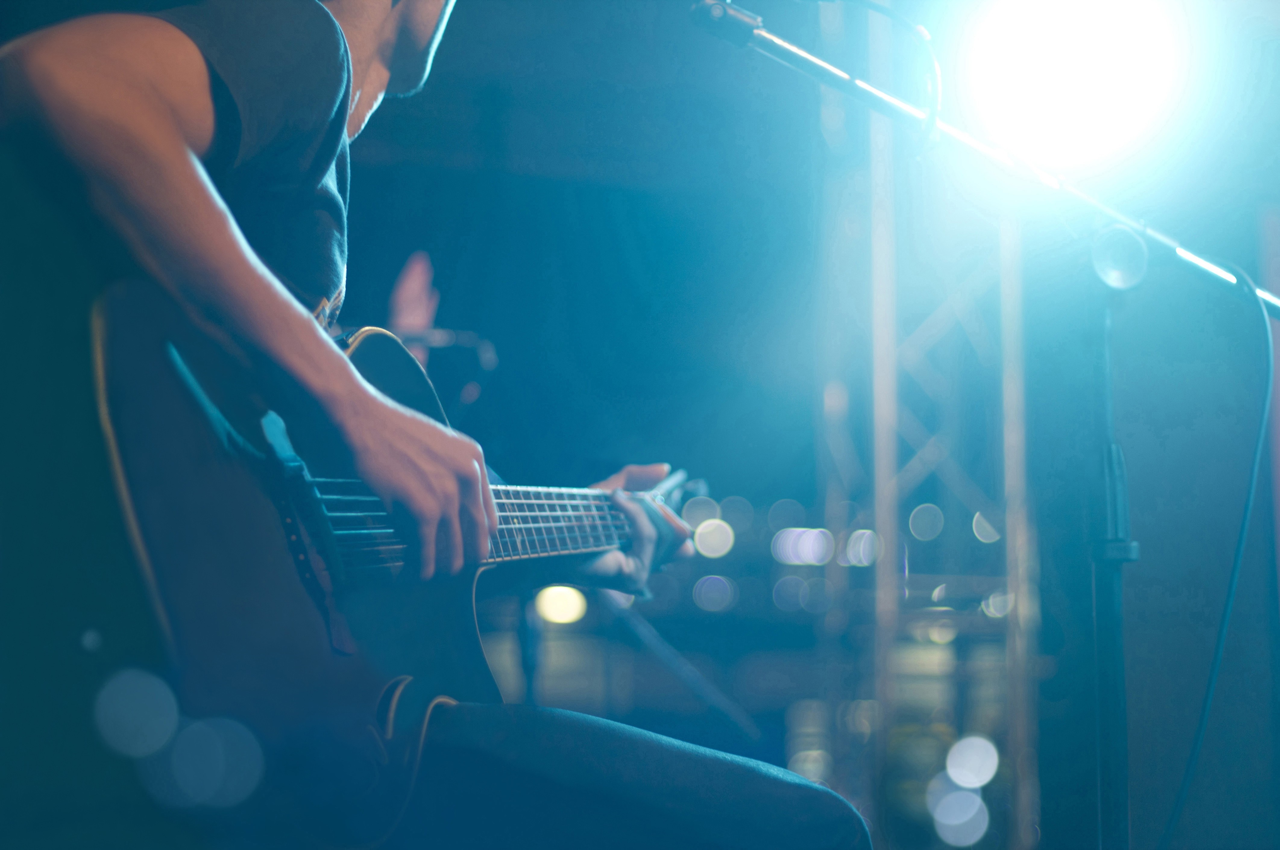 Musician playing guitar on stage with blue lights HD Wallpaper