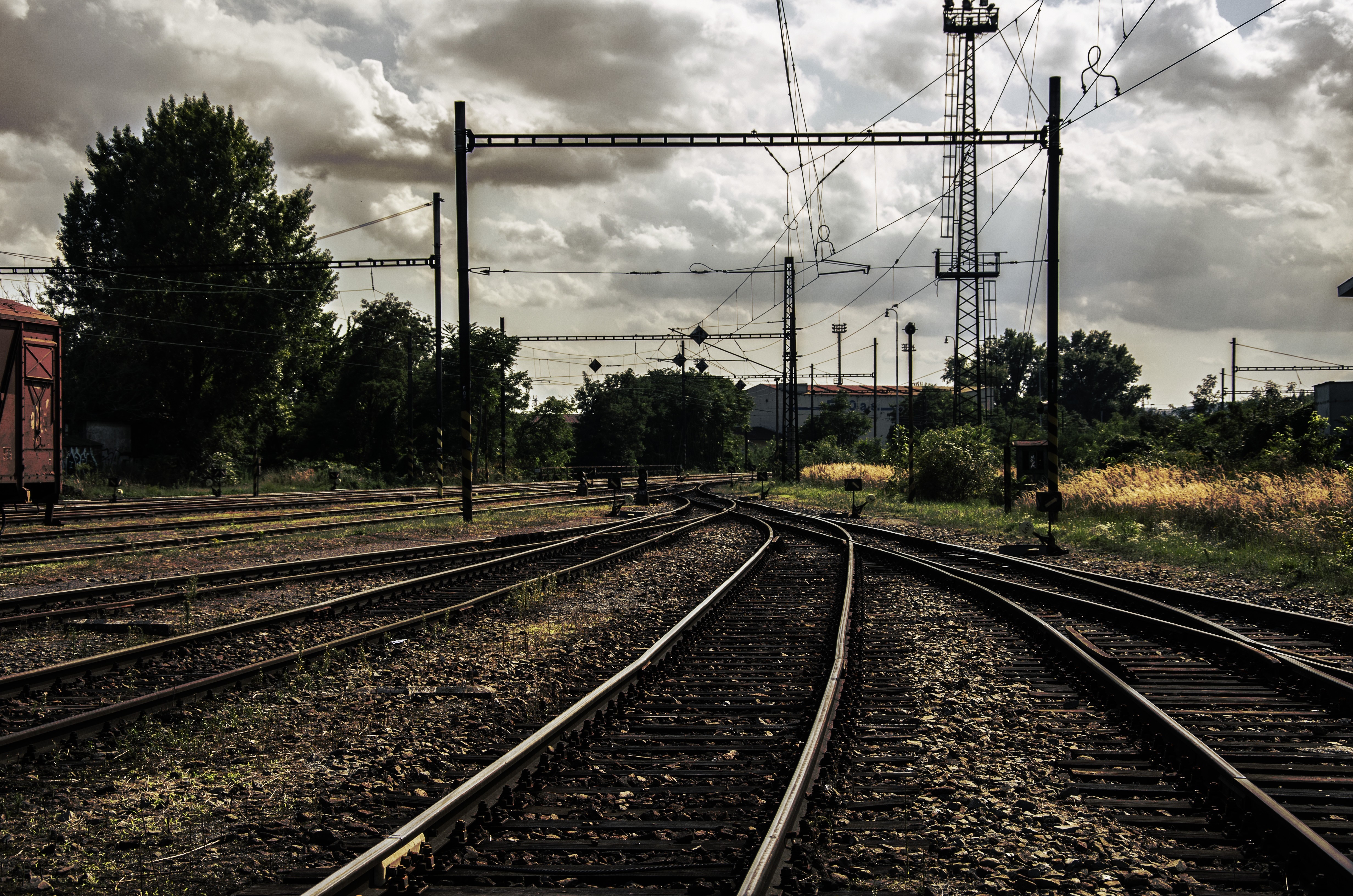 Train tracks and overhead lines in a rail yard under overcast sky HD Wallpaper