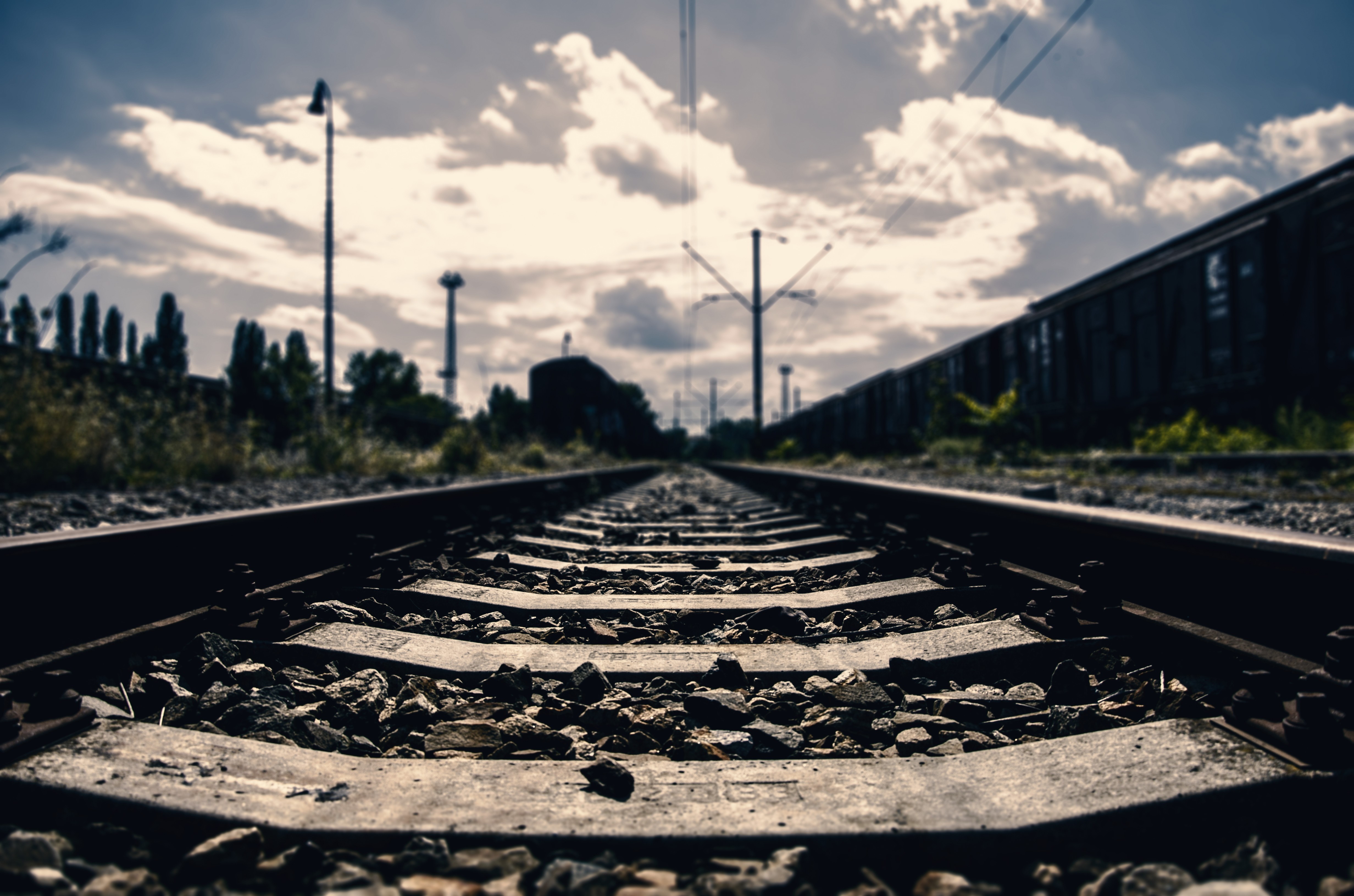 Train tracks in a rail yard with power lines and clouds HD Wallpaper