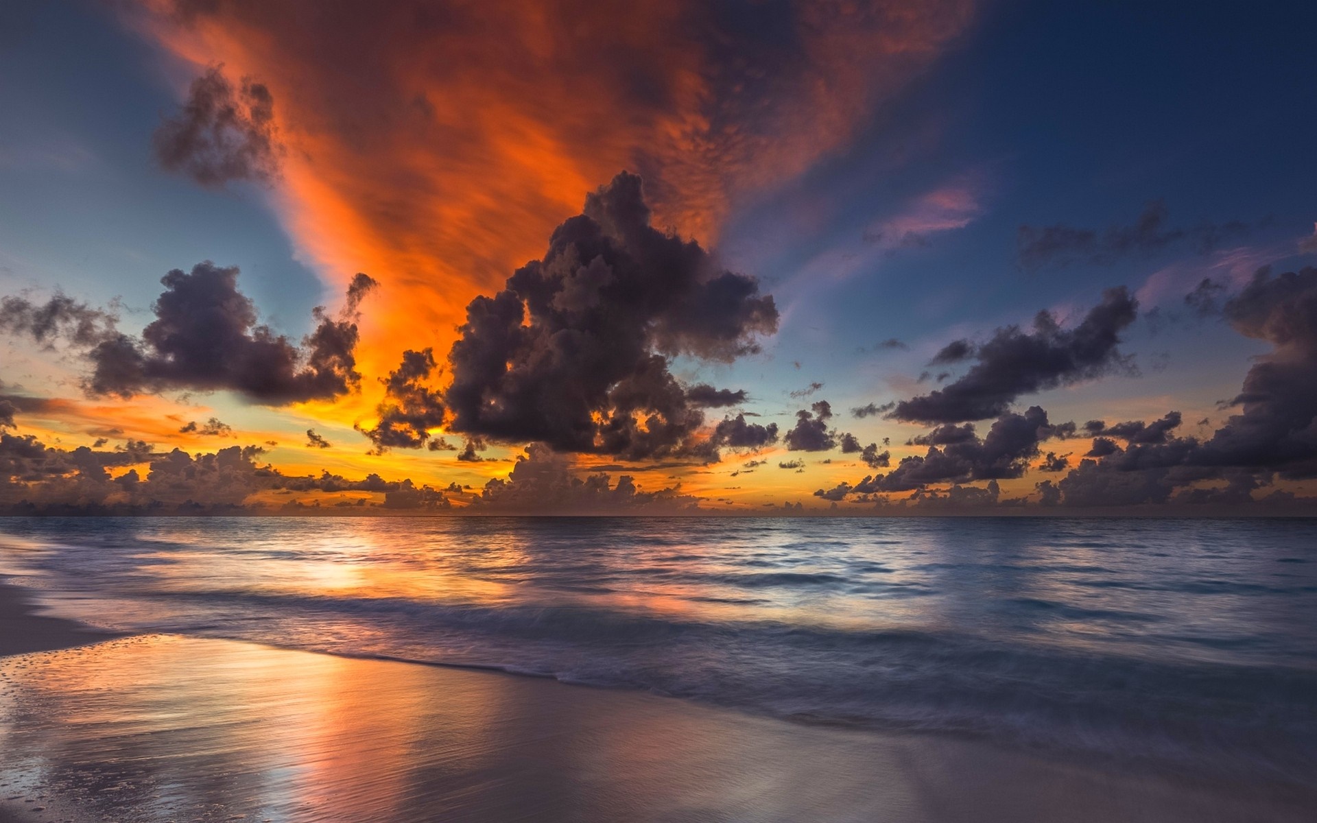 Sunset over the ocean with dramatic clouds and reflection on the beach HD Wallpaper