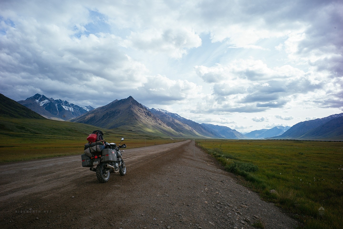 Motorcycle on a dirt road with mountains and clouds HD Wallpaper
