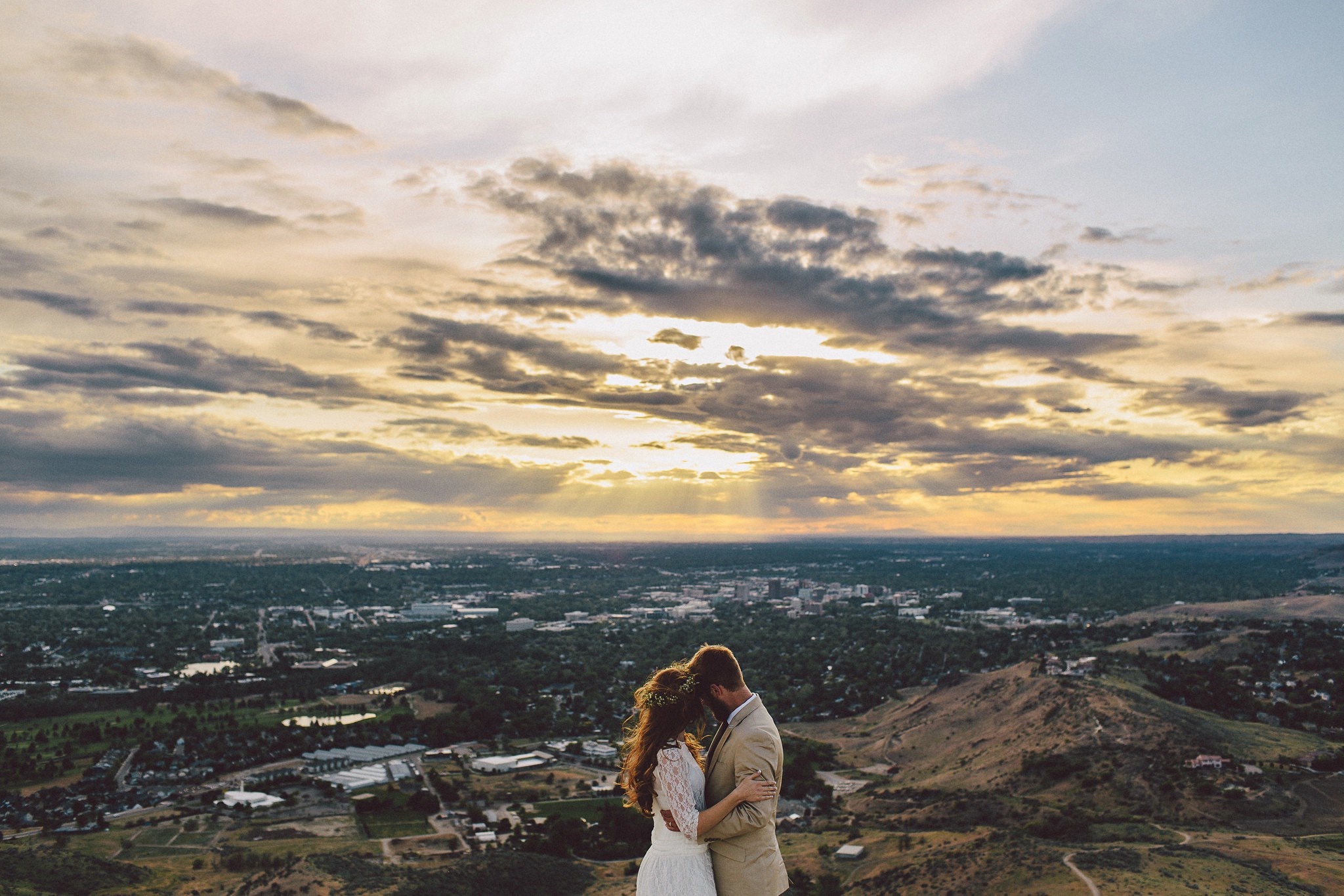 Couple on a hill overlooking a city at sunset HD Wallpaper