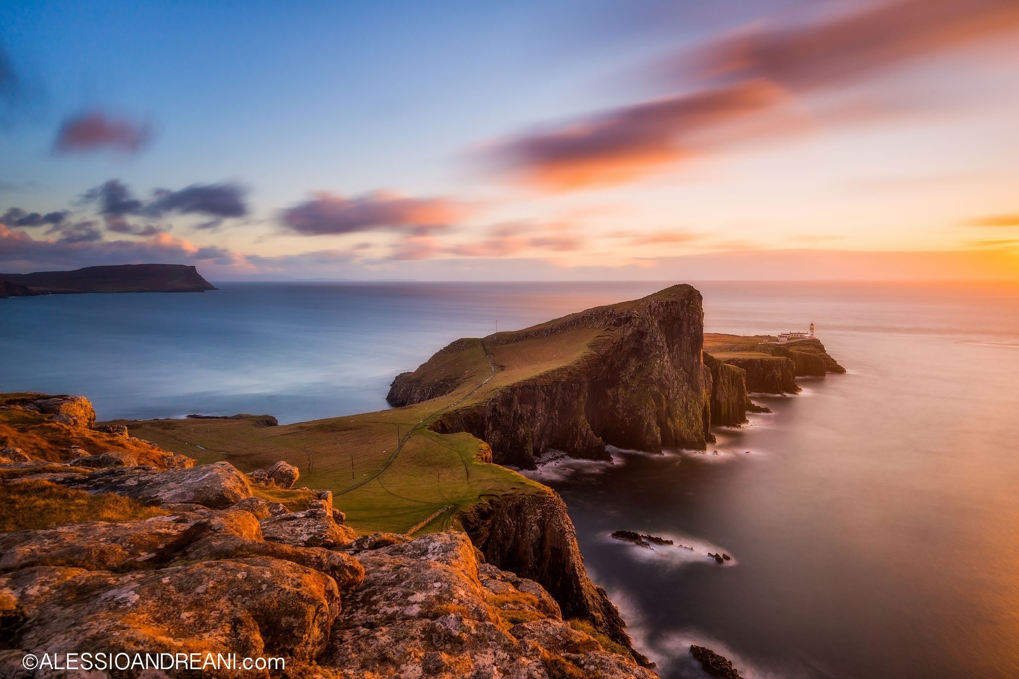 Sunset over a rocky cliff coast with a lighthouse HD Wallpaper