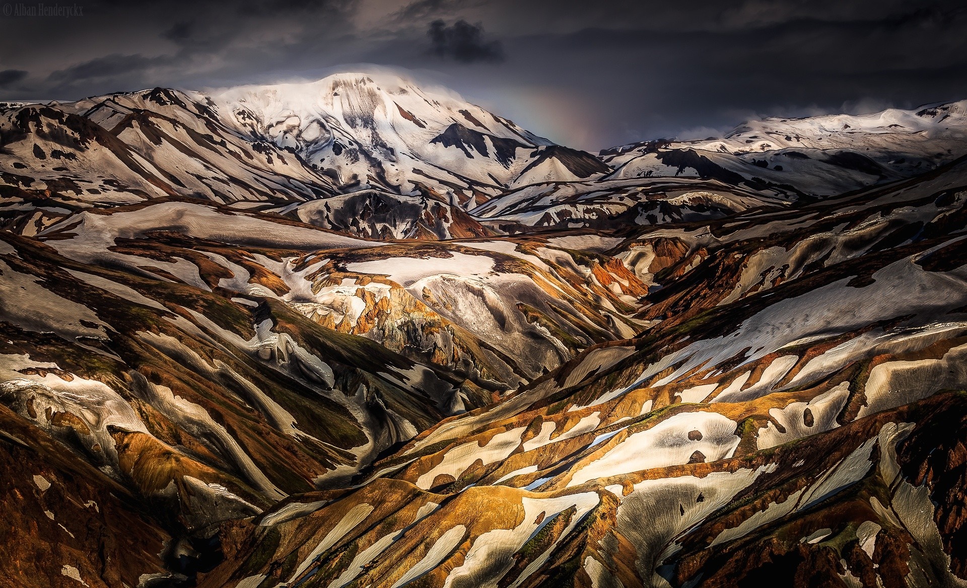 Snow-dusted mountains and colorful valleys under a dark sky HD Wallpaper