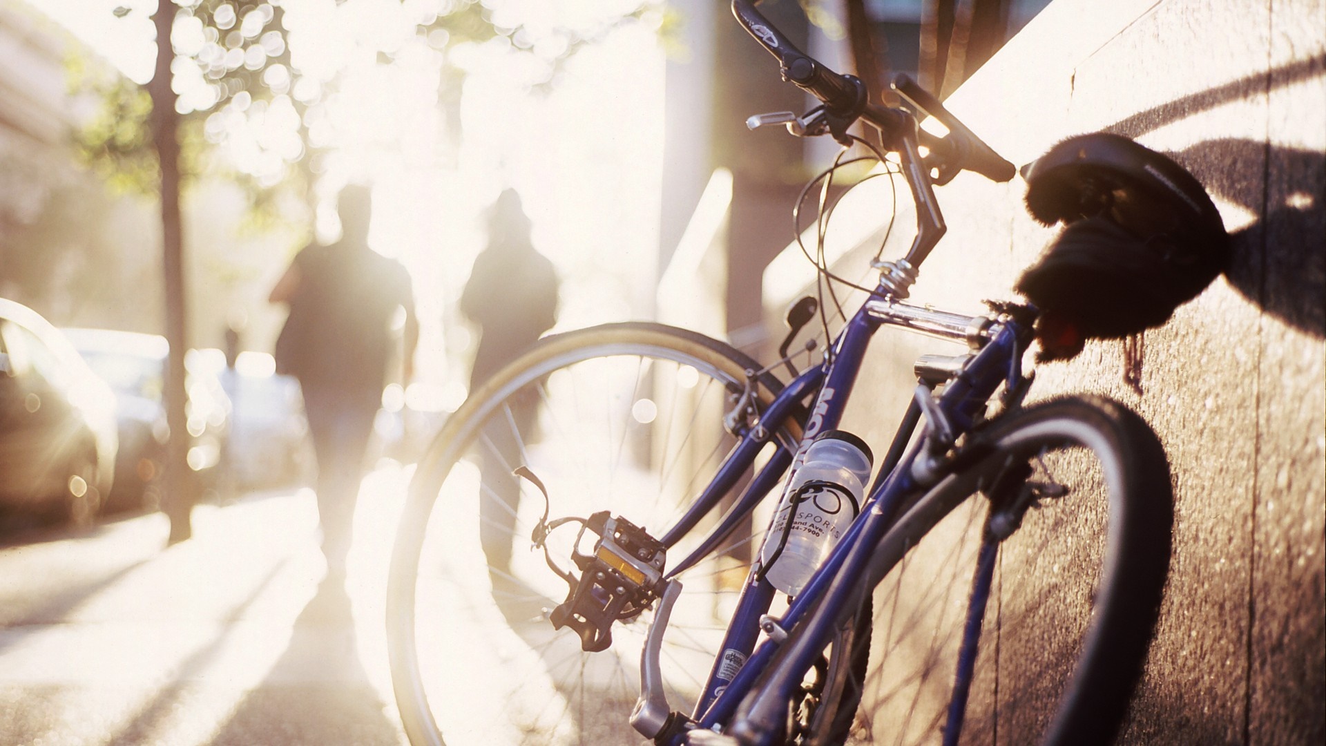 Bicycle leaning against a wall in sunlight HD Wallpaper
