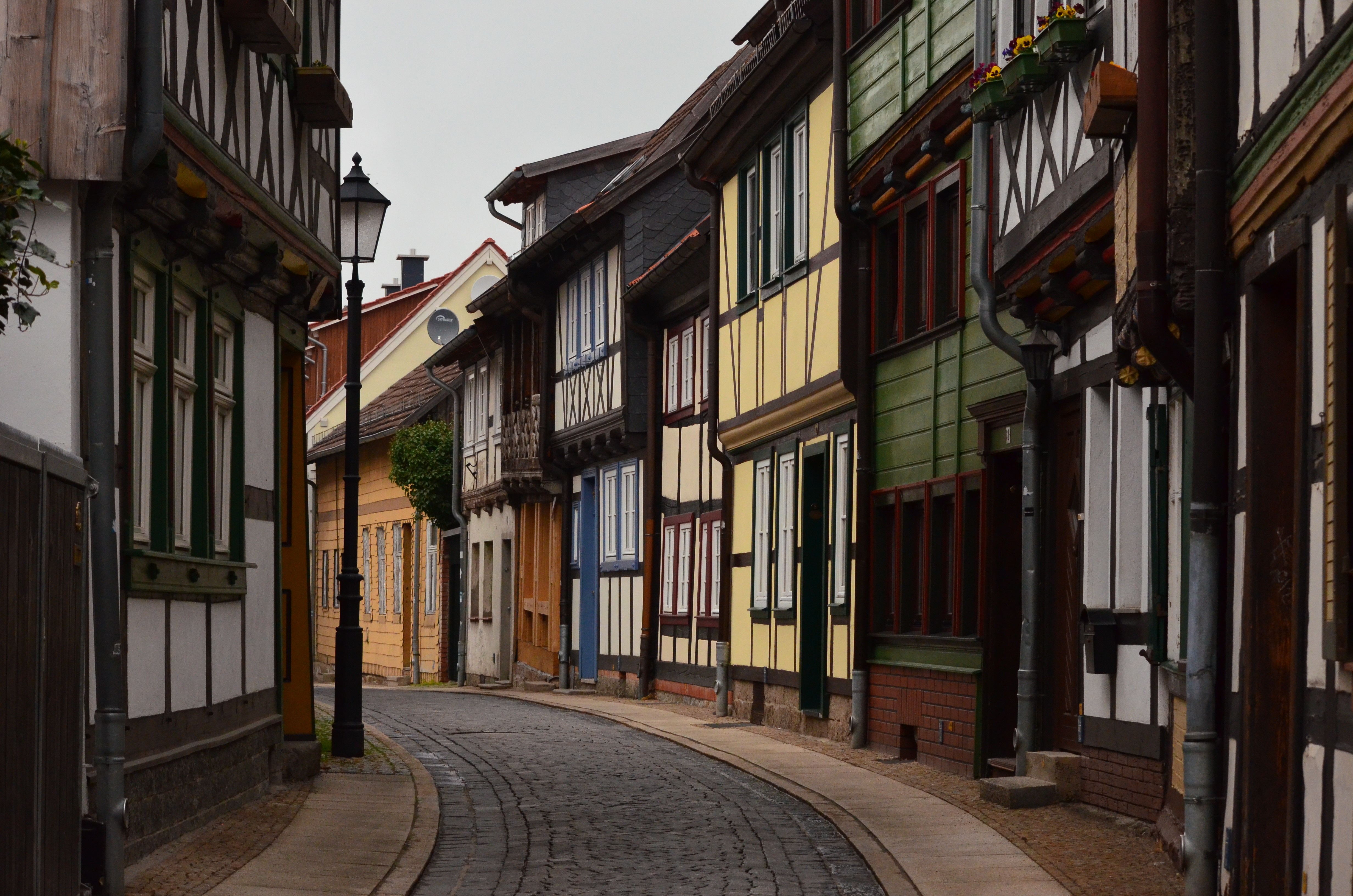 Cobblestone street lined with colorful half-timbered houses HD Wallpaper