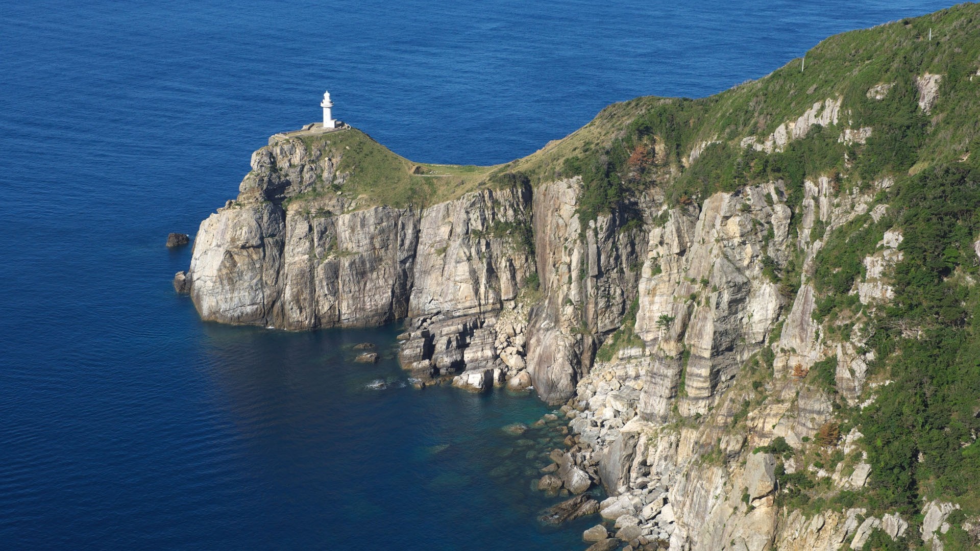 Lighthouse on a rocky cliff overlooking the sea HD Wallpaper