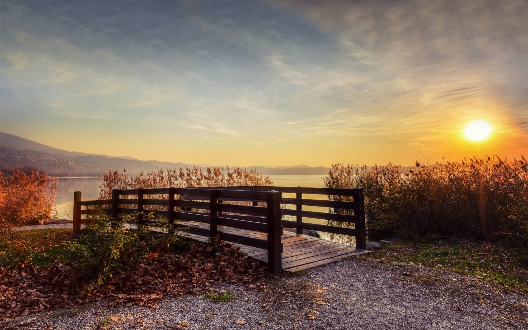 Wooden bridge over a lake at sunset with reeds HD Wallpaper