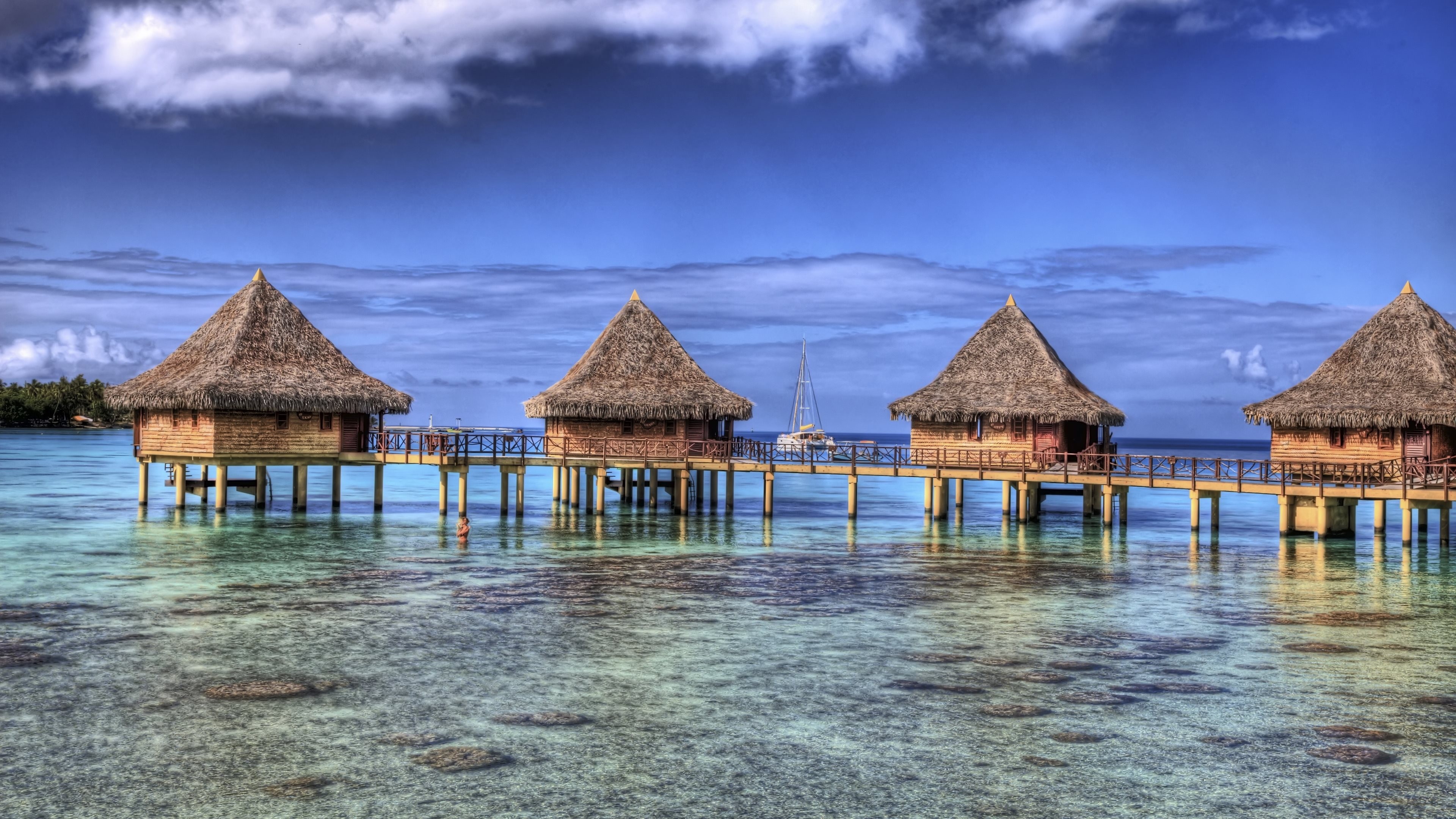 Overwater bungalows in a tropical lagoon with a sailboat HD Wallpaper