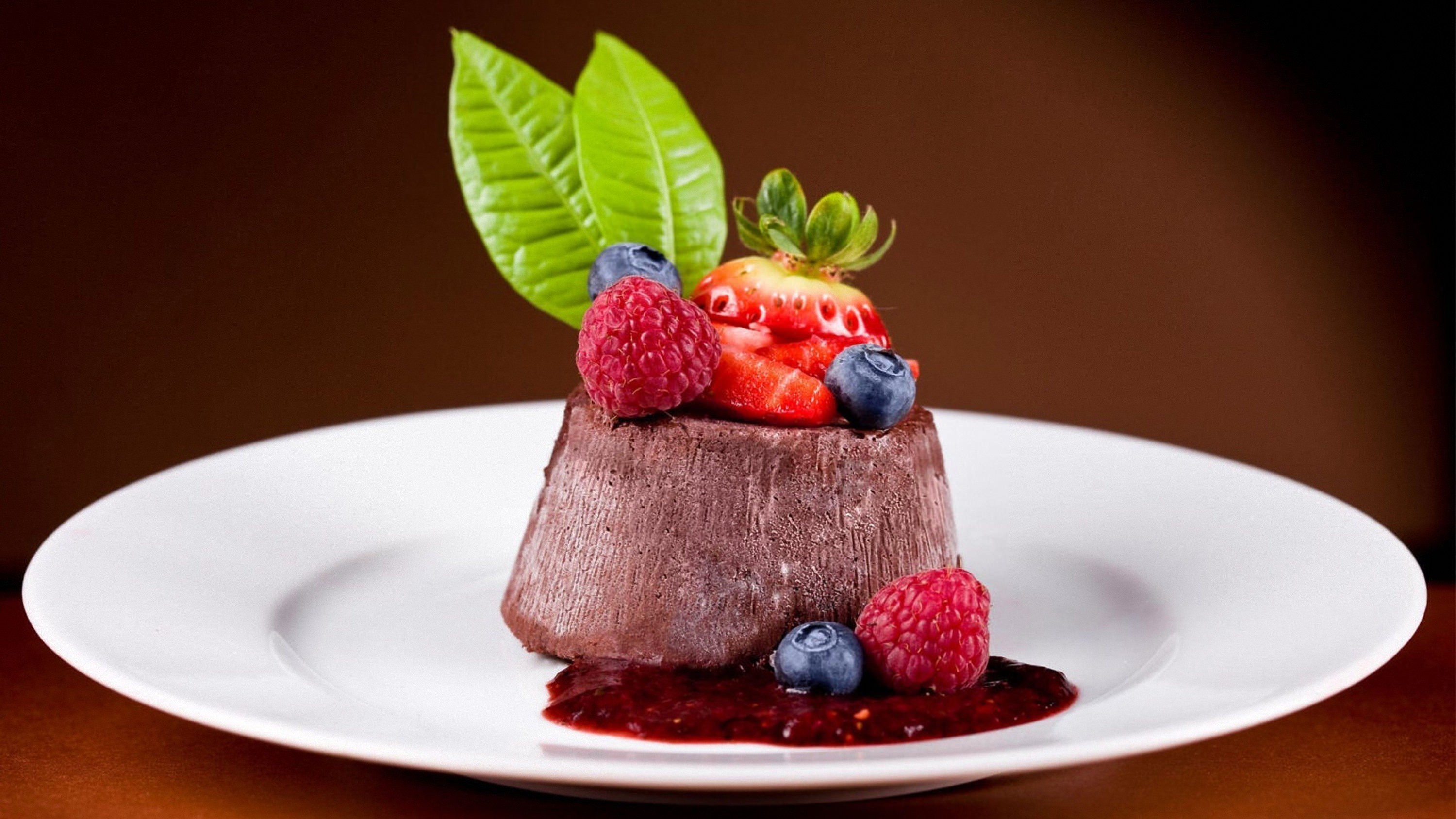 Chocolate dessert with berries and leaves on a white plate HD Wallpaper