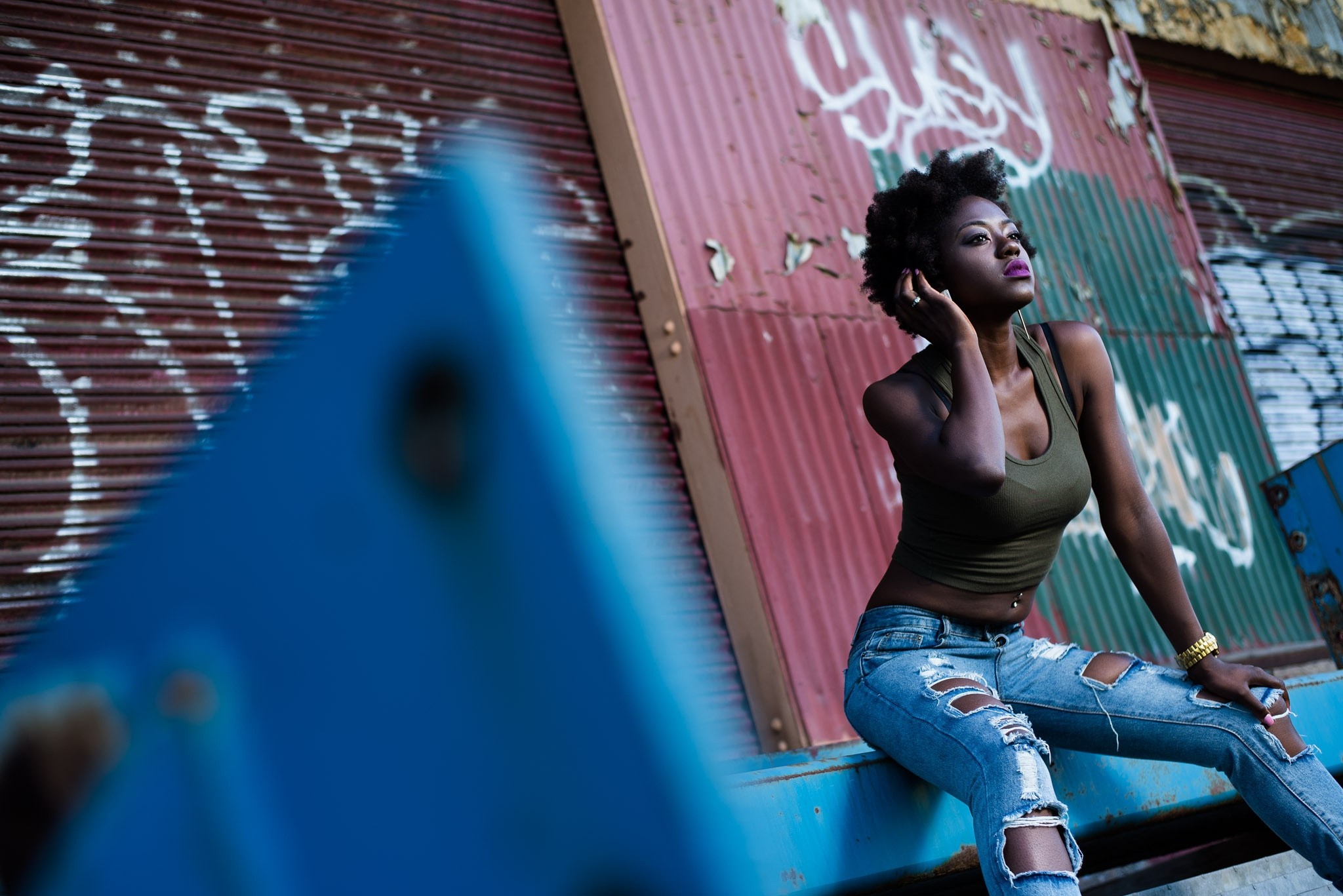 Woman in torn jeans sitting by graffiti wall HD Wallpaper