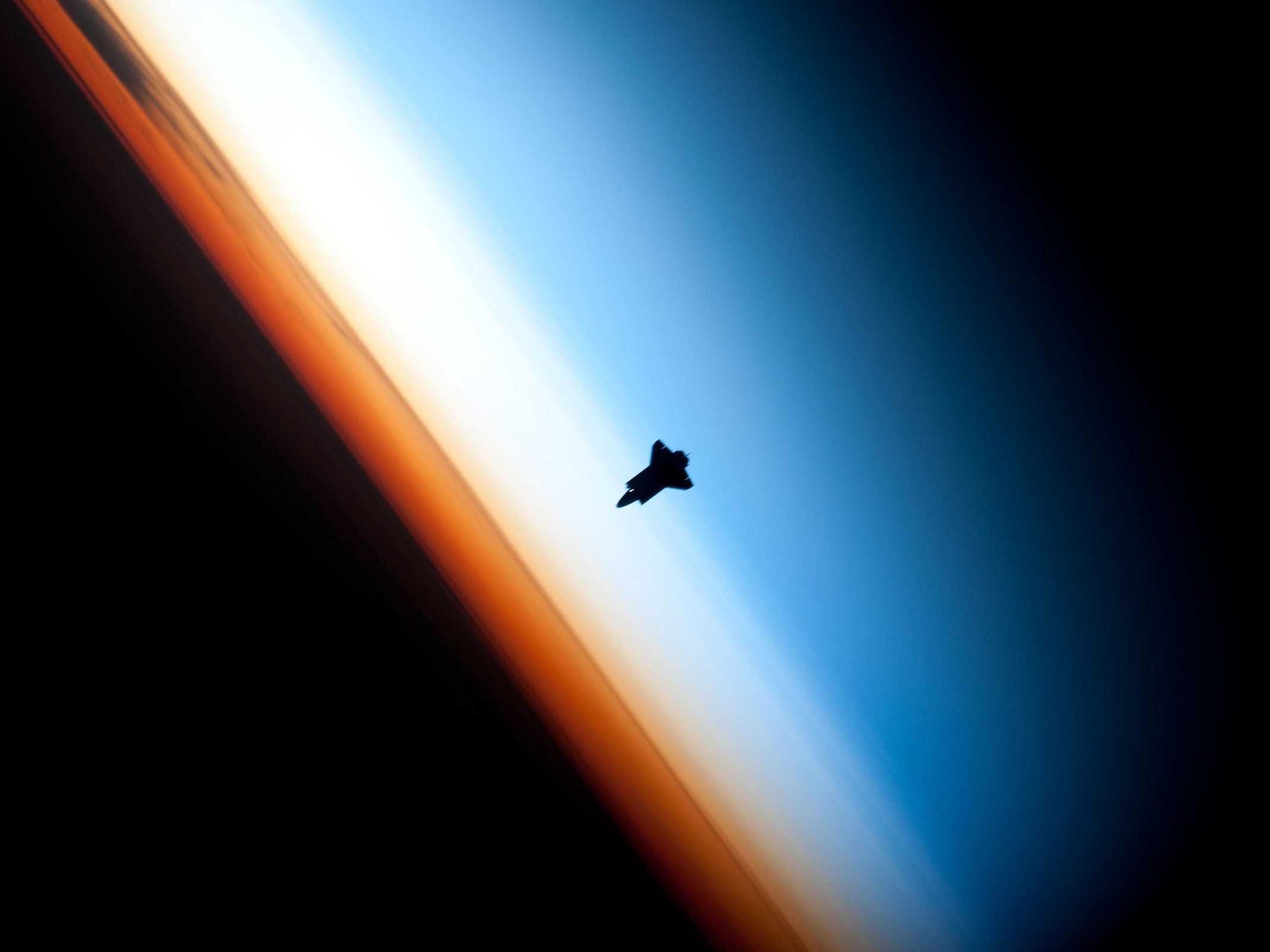 Space shuttle silhouette against Earth's atmosphere HD Wallpaper