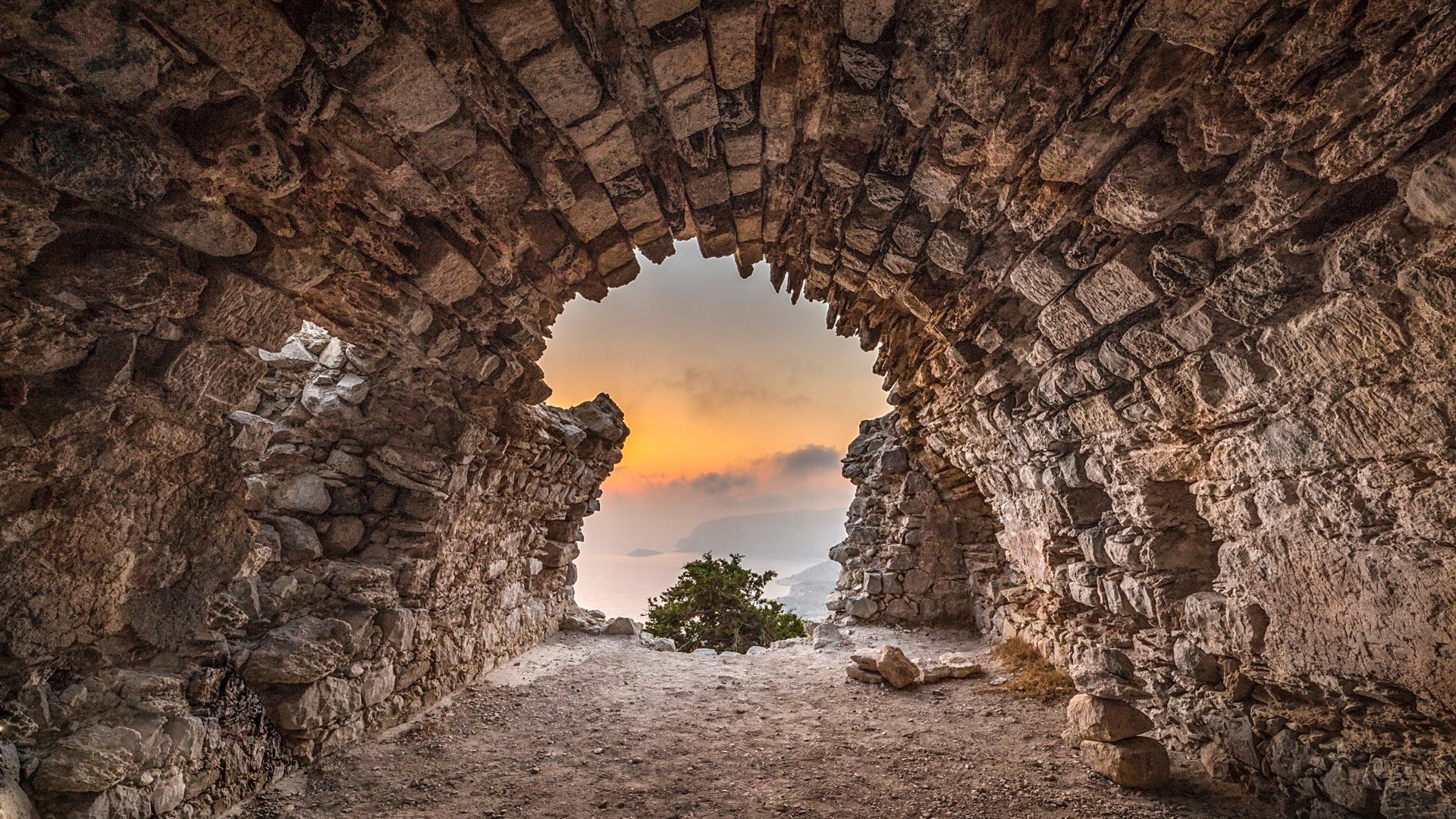 Ruins of an ancient stone archway overlooking a sunset sea landscape HD Wallpaper