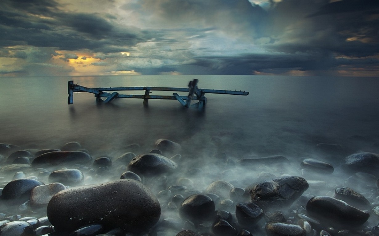 Ruined pier in the sea at sunset with misty shore HD Wallpaper