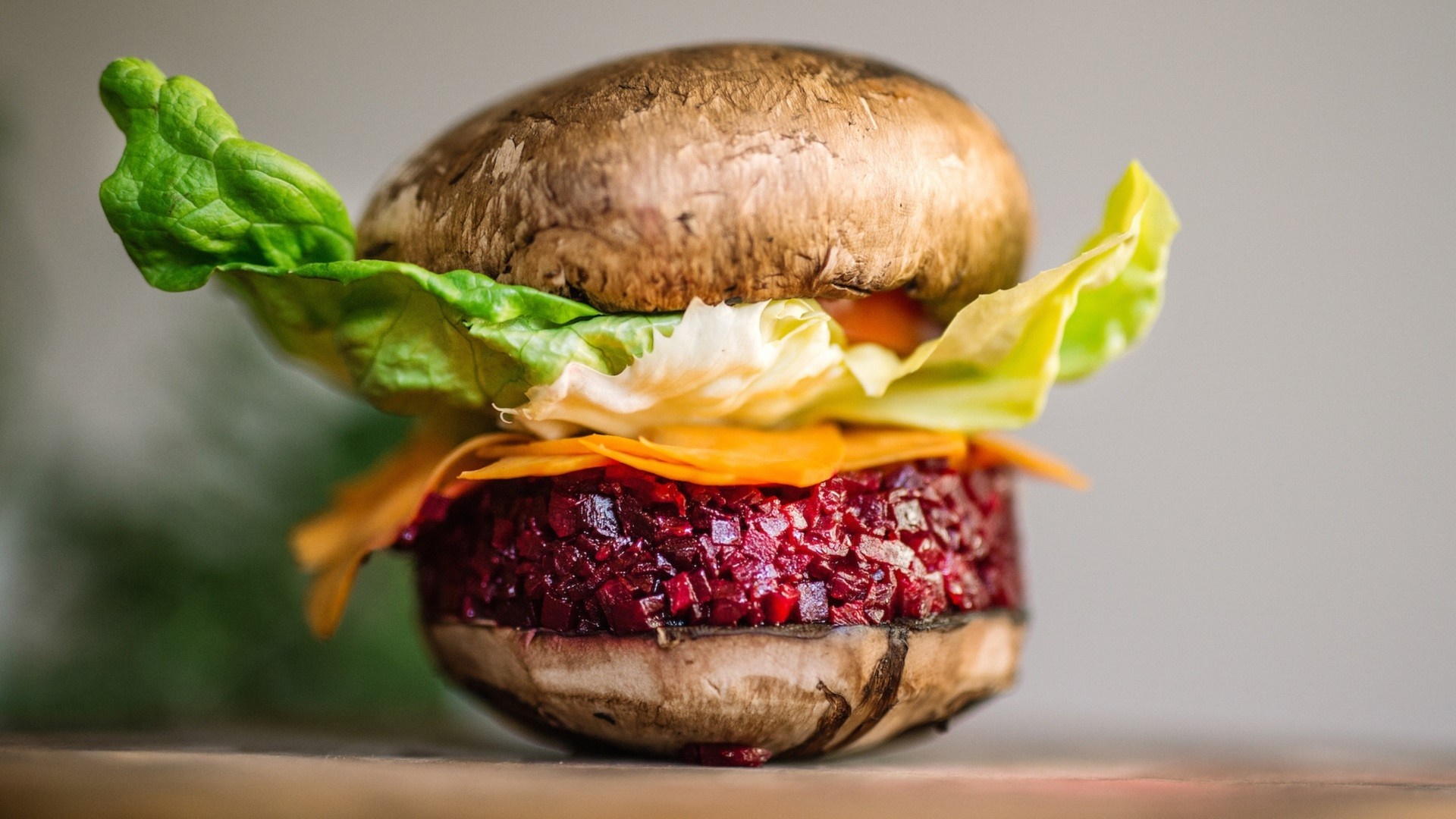 Mushroom burger with beet patty and shredded carrots HD Wallpaper