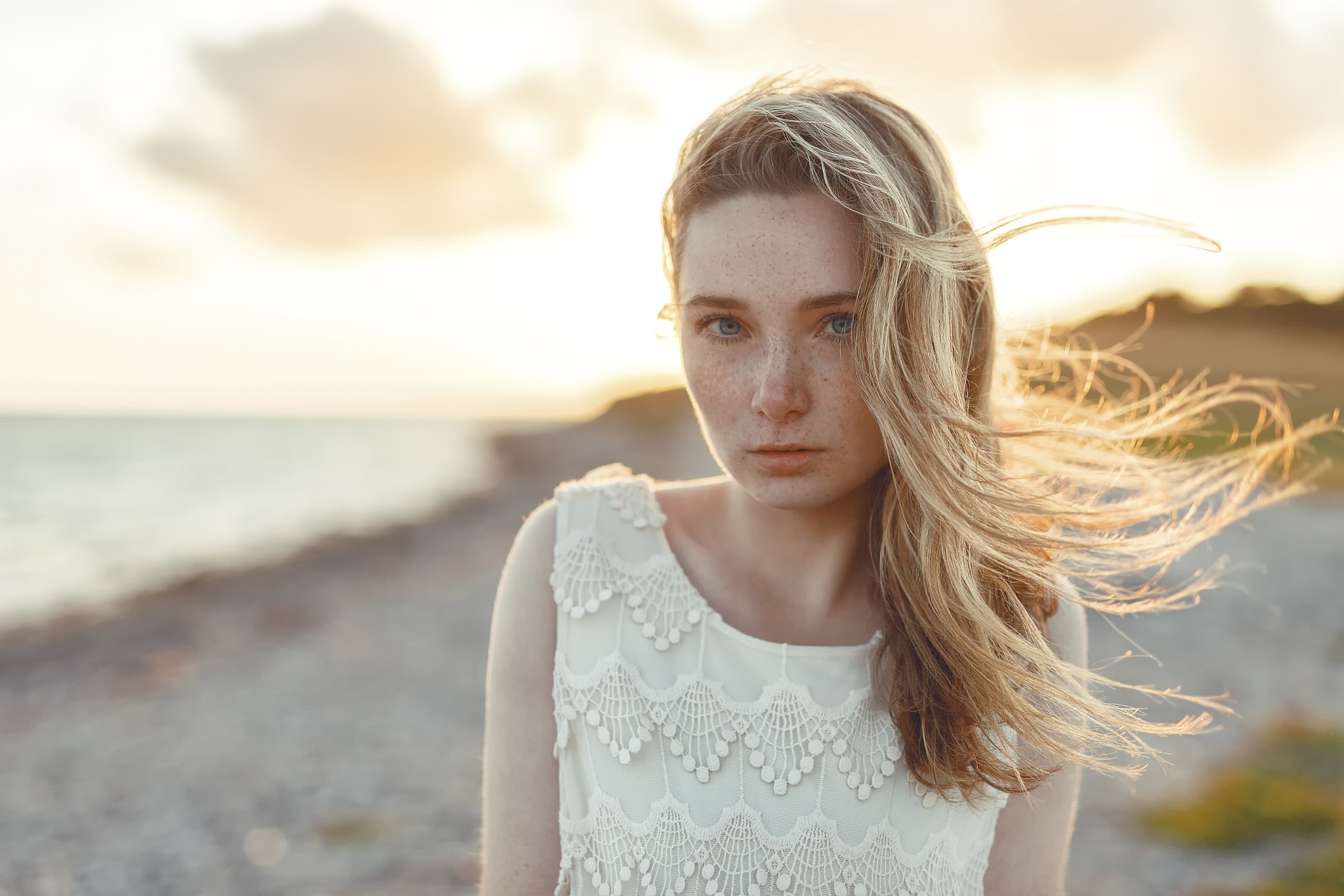 Woman with freckles and windblown hair on a beach HD Wallpaper
