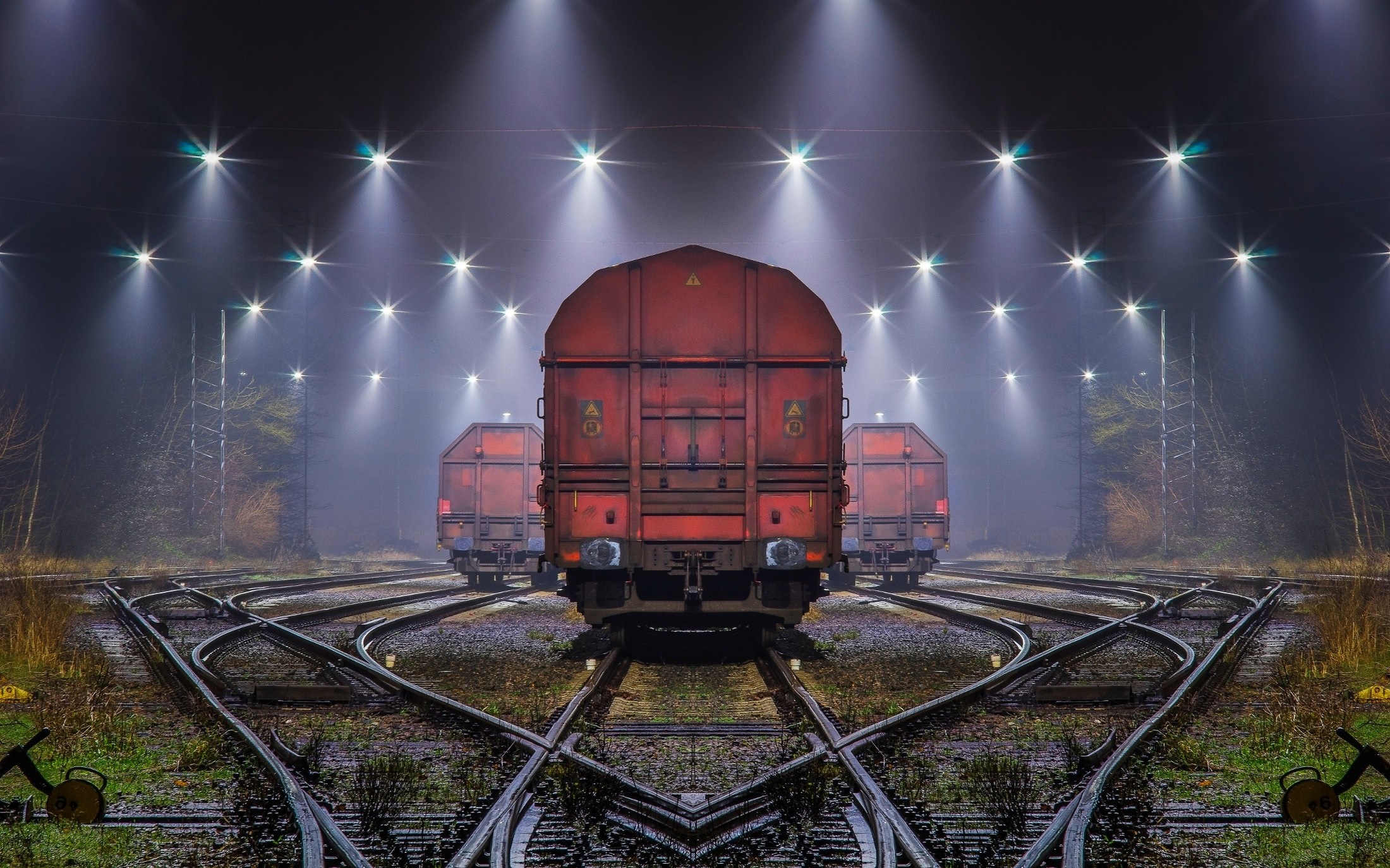 Red freight trains on railway tracks at night with spotlights HD Wallpaper