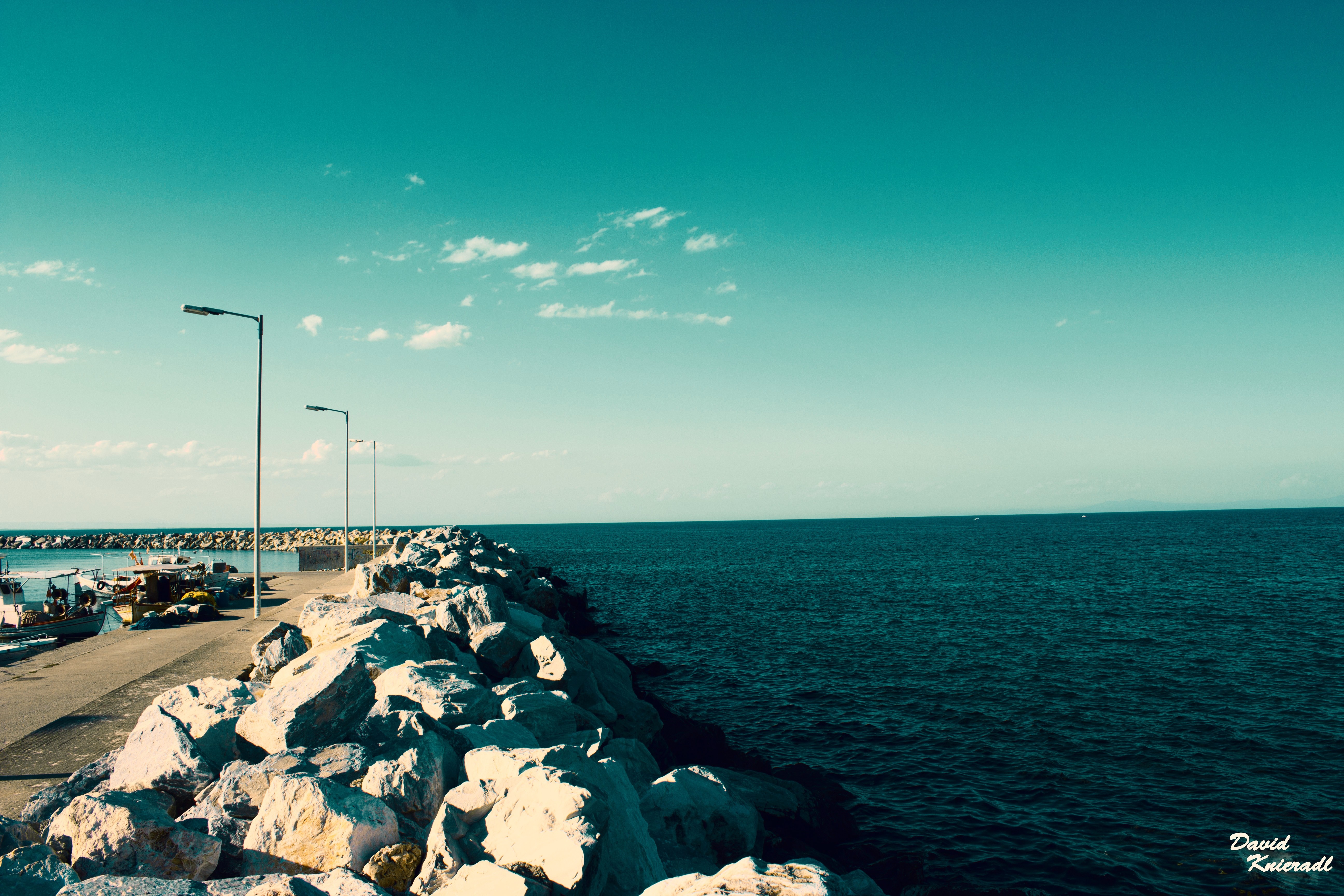 Rocky pier with streetlights and boats by the sea HD Wallpaper