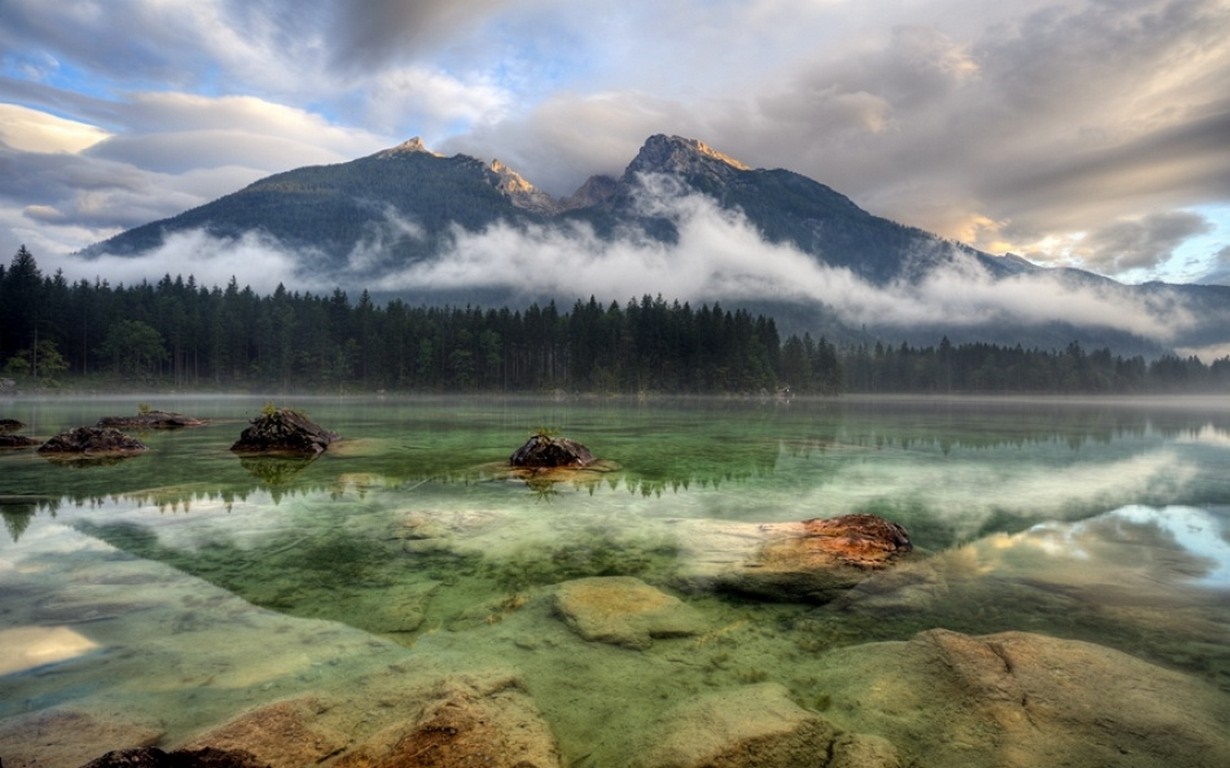 Misty mountains reflected in a clear lake at sunrise HD Wallpaper