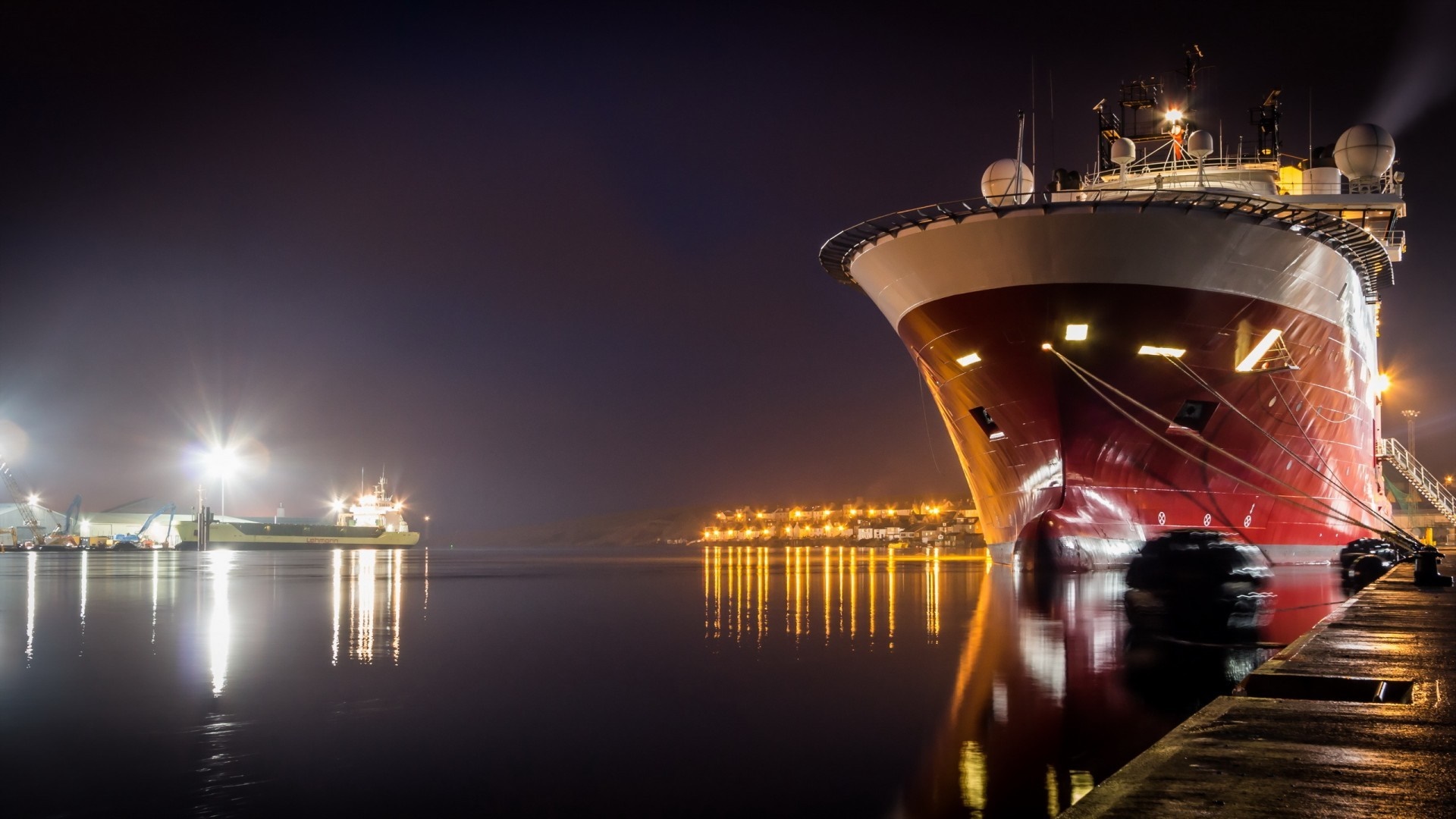 Large red ship docked at night with city lights reflection HD Wallpaper