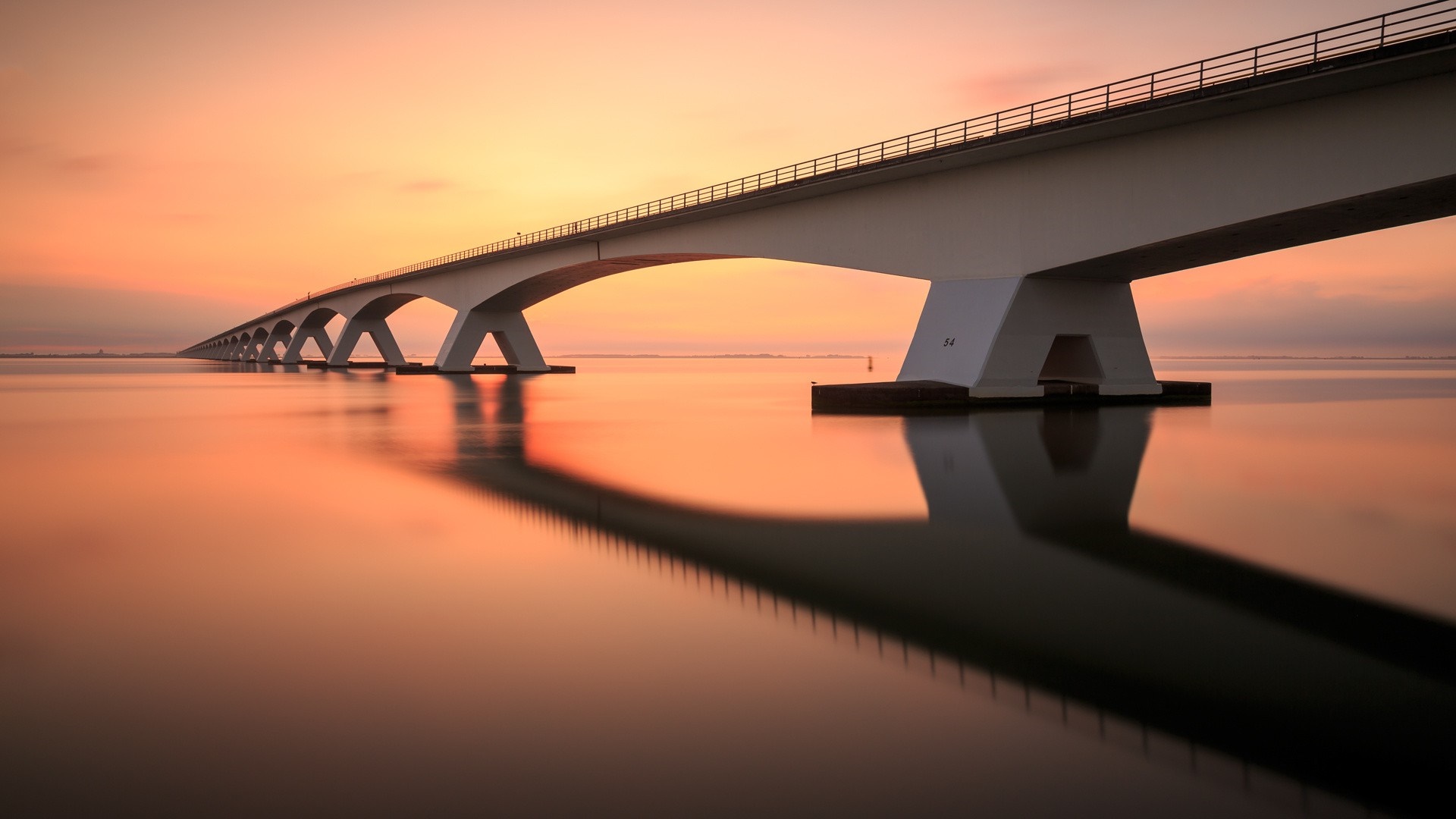Bridge over water at sunset with reflection HD Wallpaper