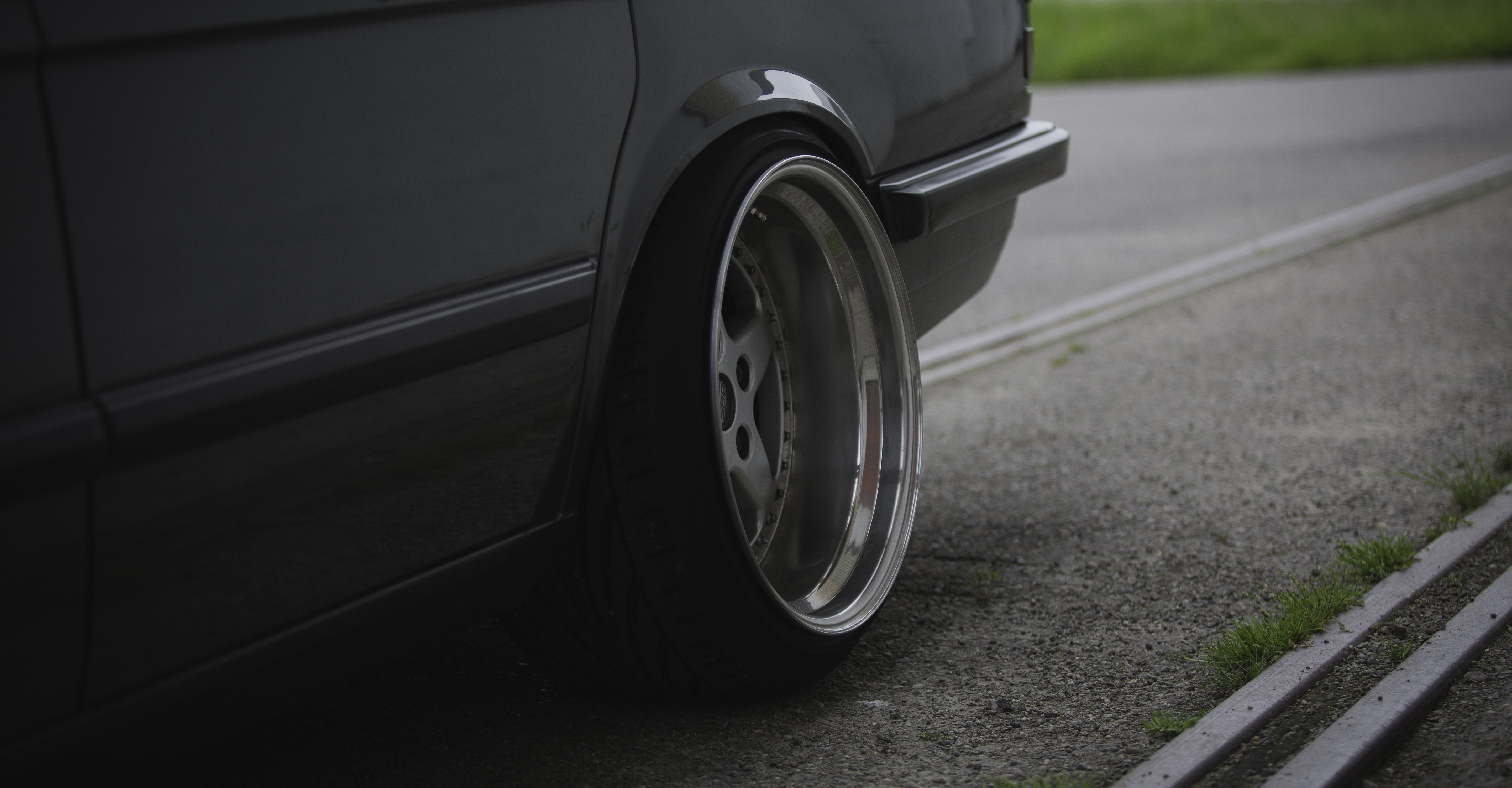 Close-up of a dark car's rear wheel and bumper HD Wallpaper