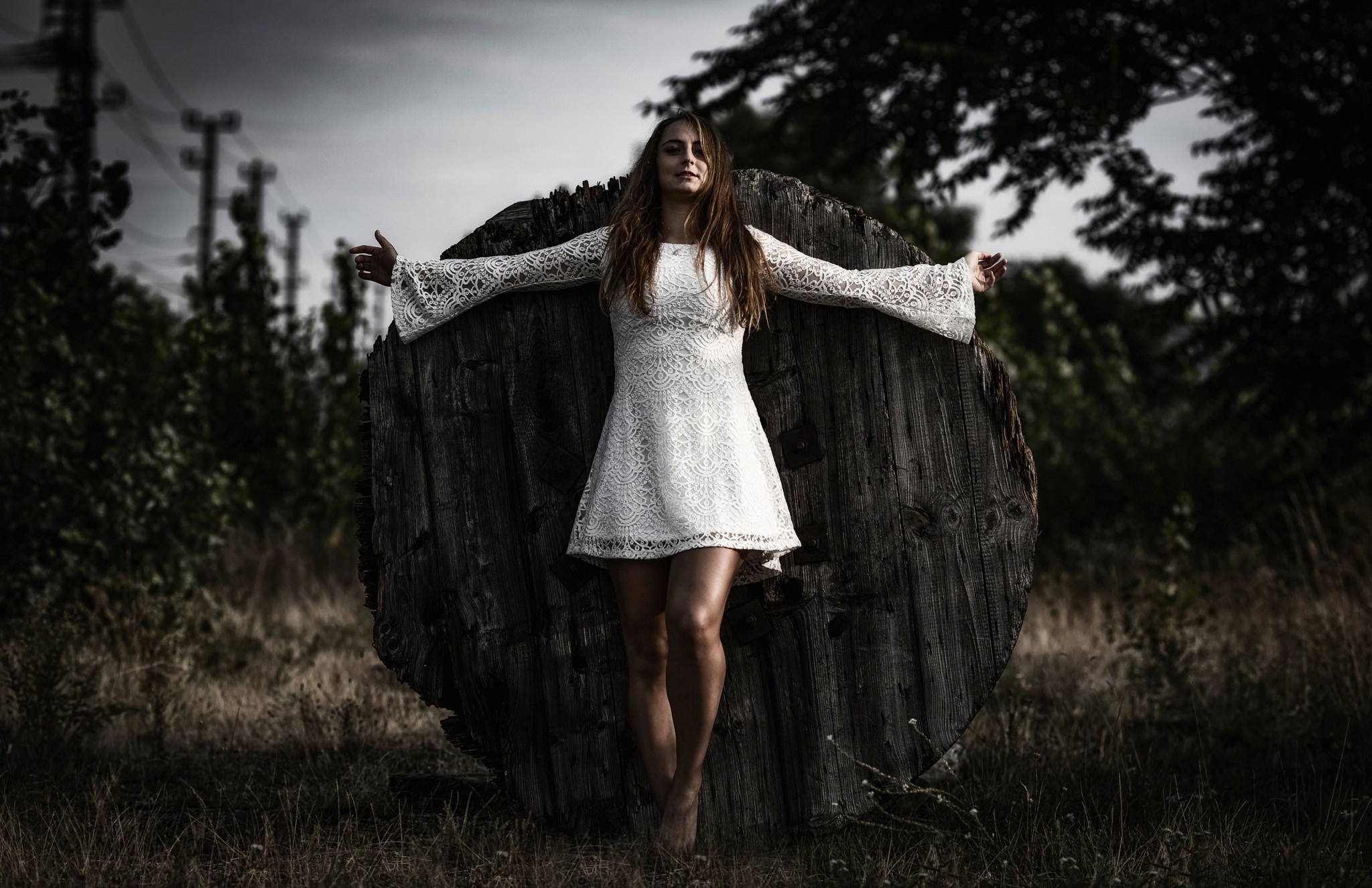 Woman in white dress standing by a wooden spool HD Wallpaper