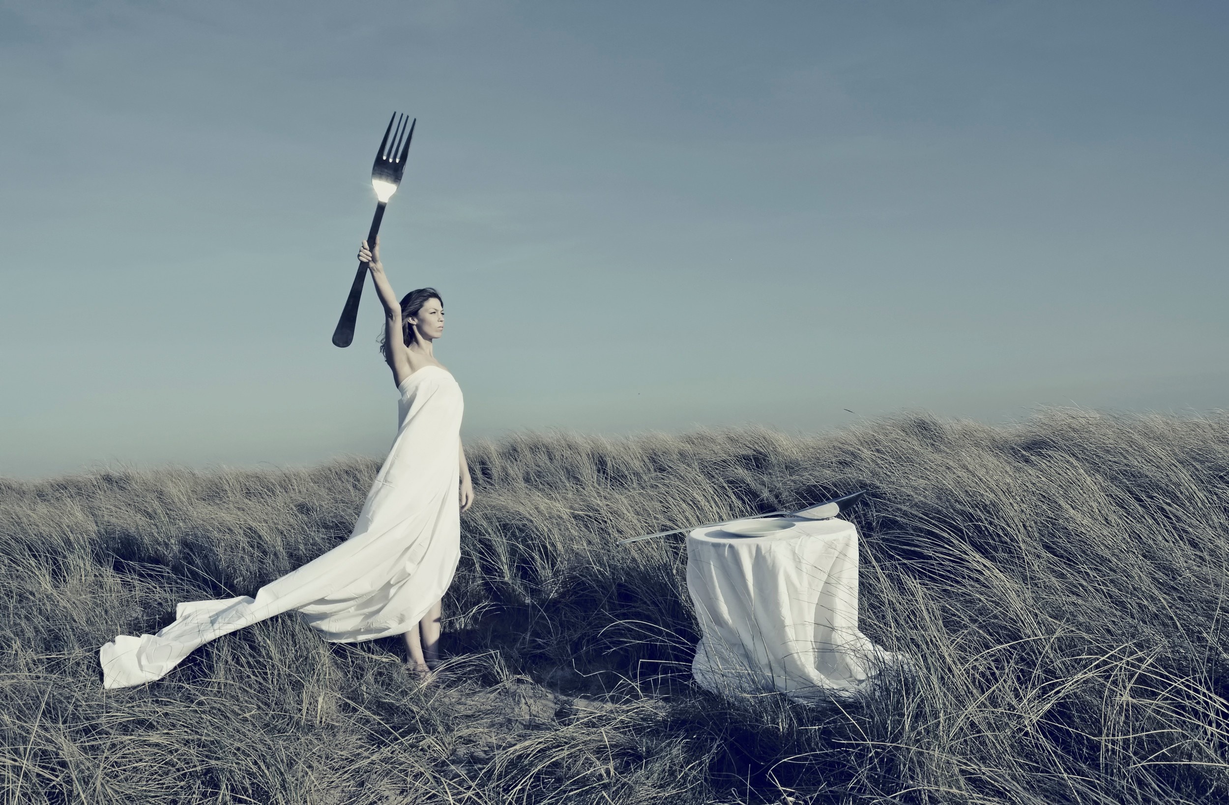 Woman in white dress holding a giant fork outdoors HD Wallpaper