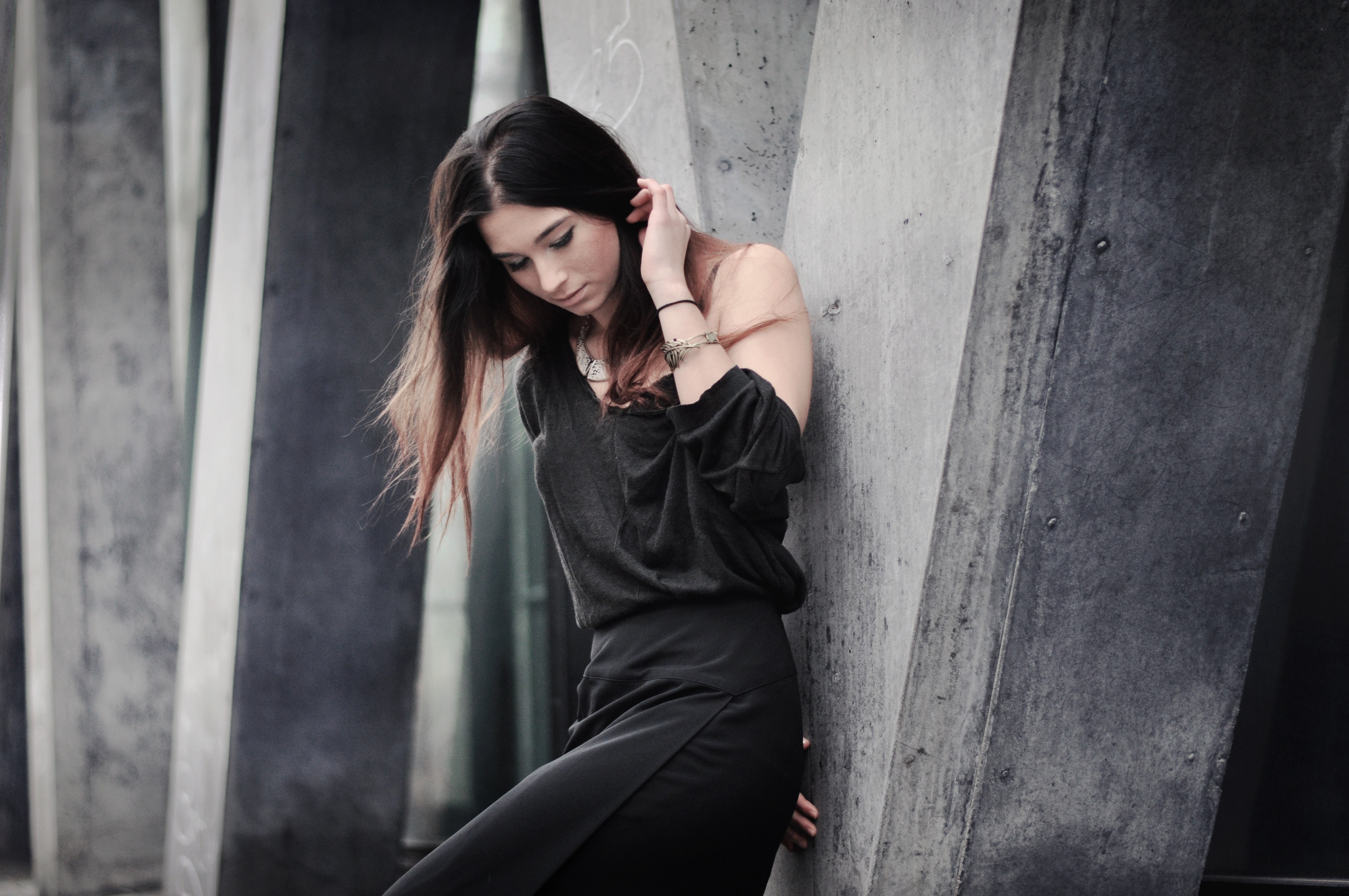 Woman in black dress leaning against concrete structure HD Wallpaper