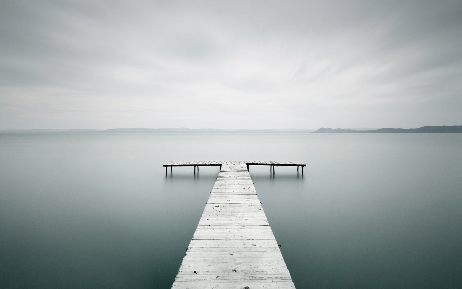 Long exposure of a wooden pier on a calm lake HD Wallpaper