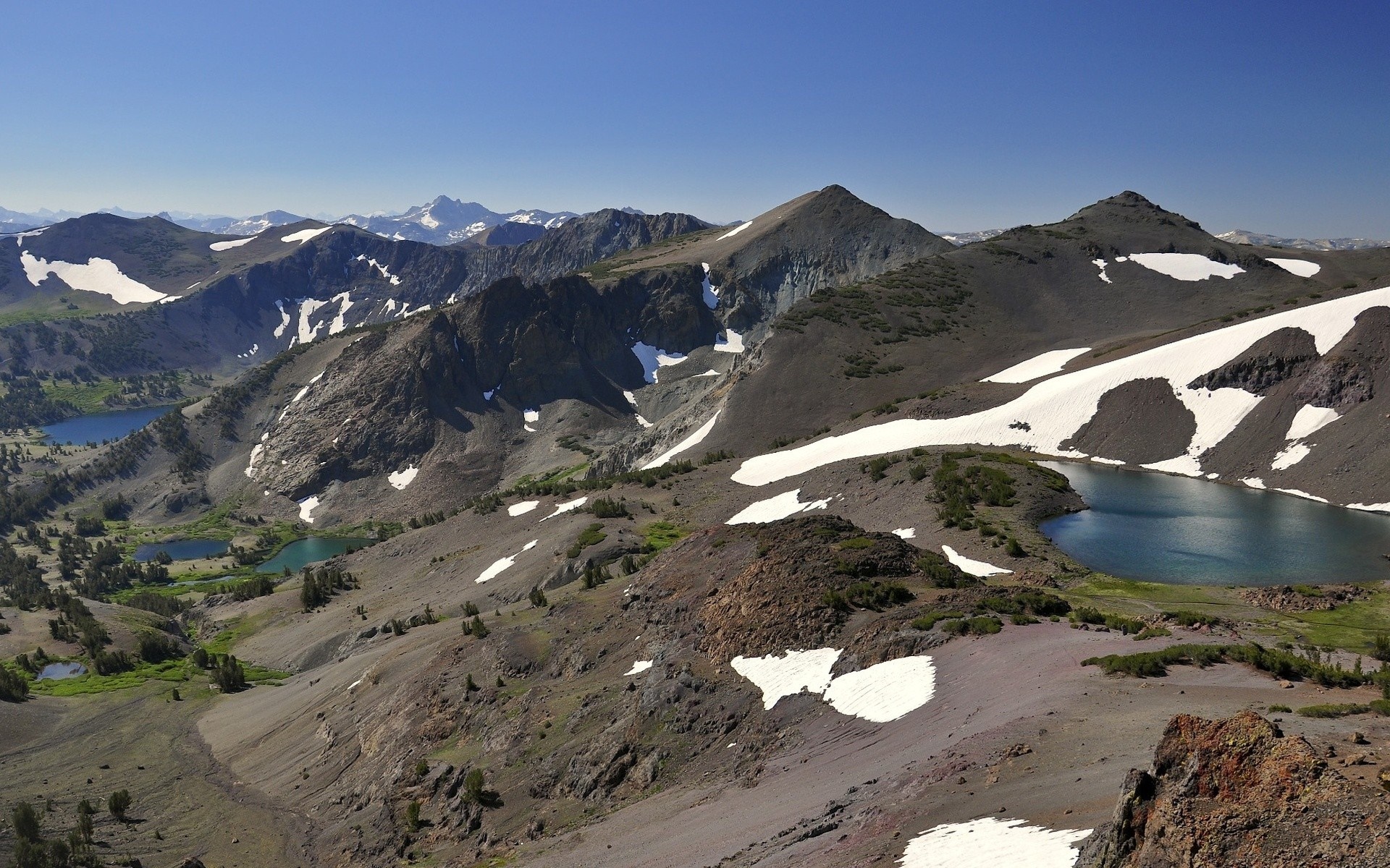 Mountain range with lakes and snow patches HD Wallpaper