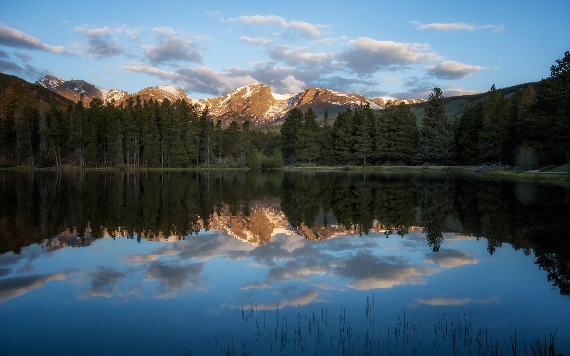 Mountain range reflected in a calm lake at sunrise HD Wallpaper