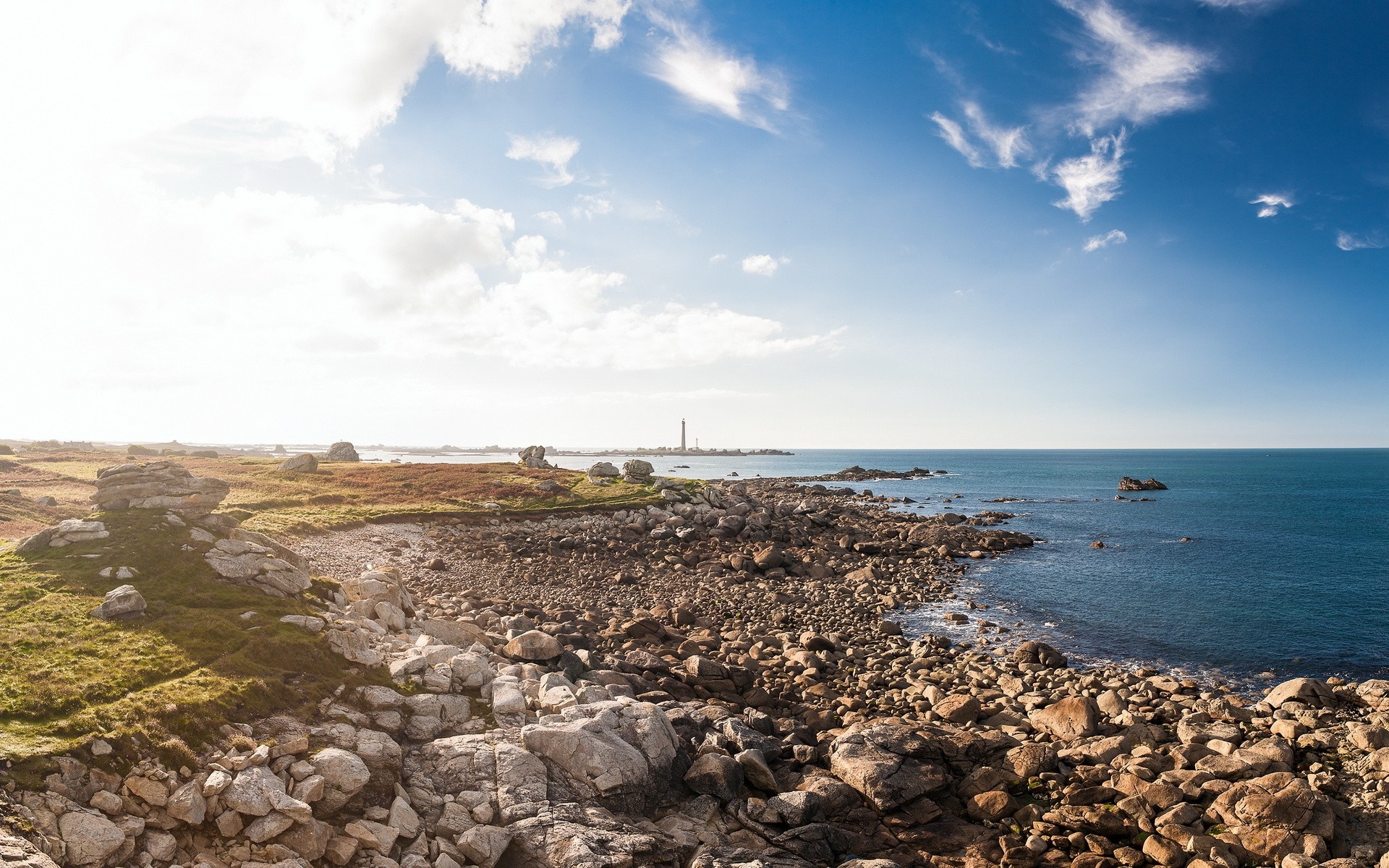 Rocky coast with lighthouse and blue sky HD Wallpaper