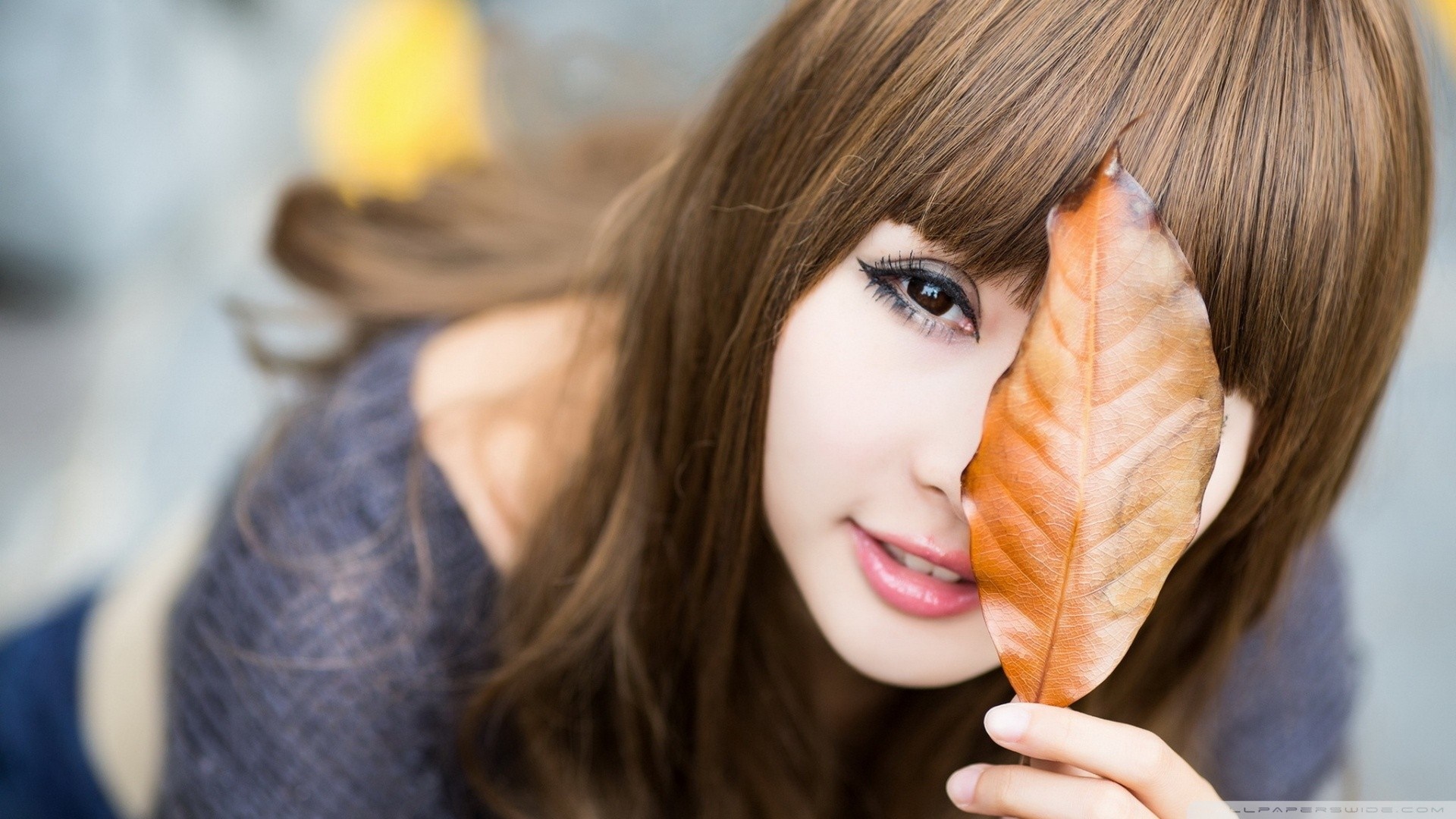 Young woman with brown hair holding a leaf HD Wallpaper