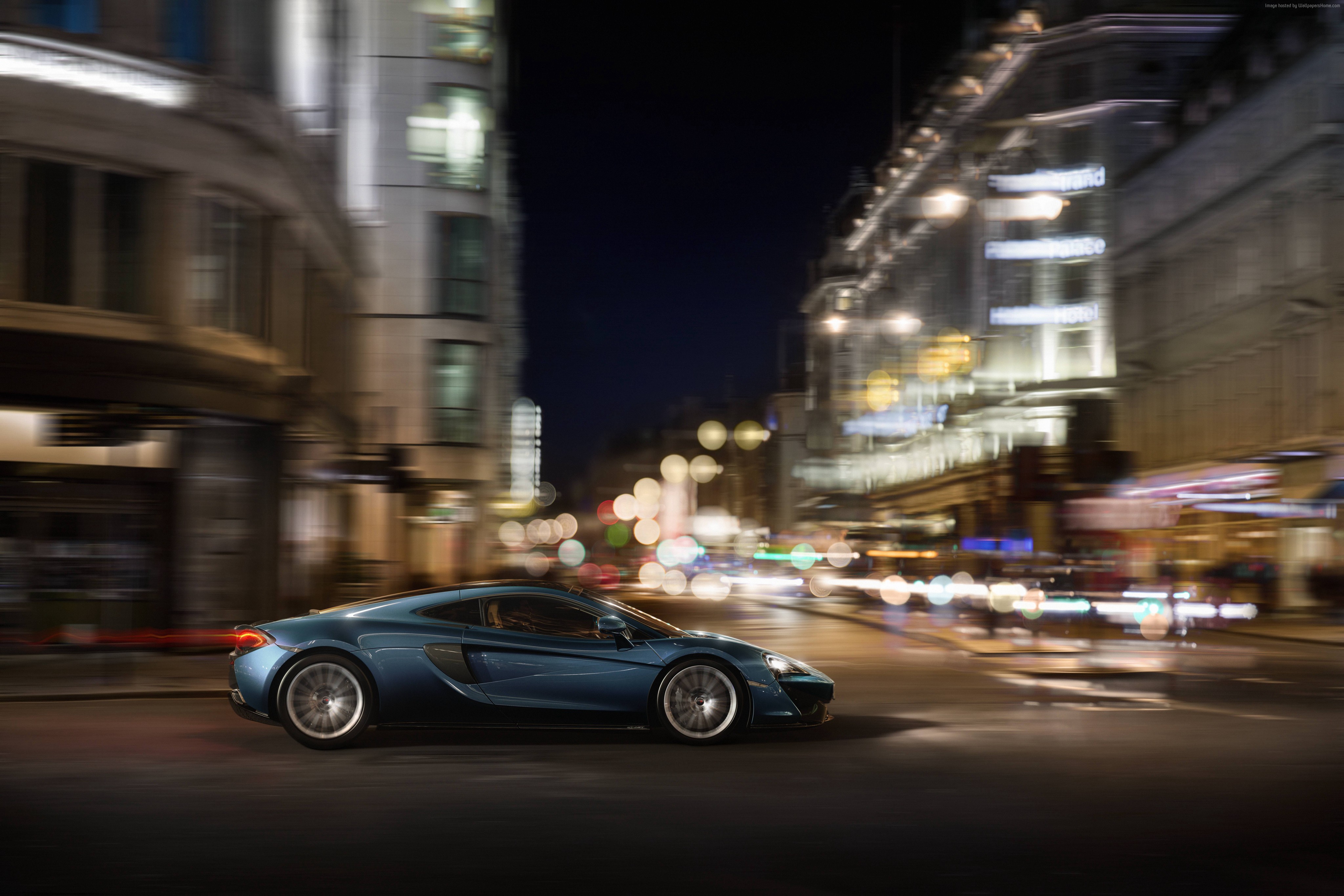 Blue McLaren sports car driving on a city street at night HD Wallpaper