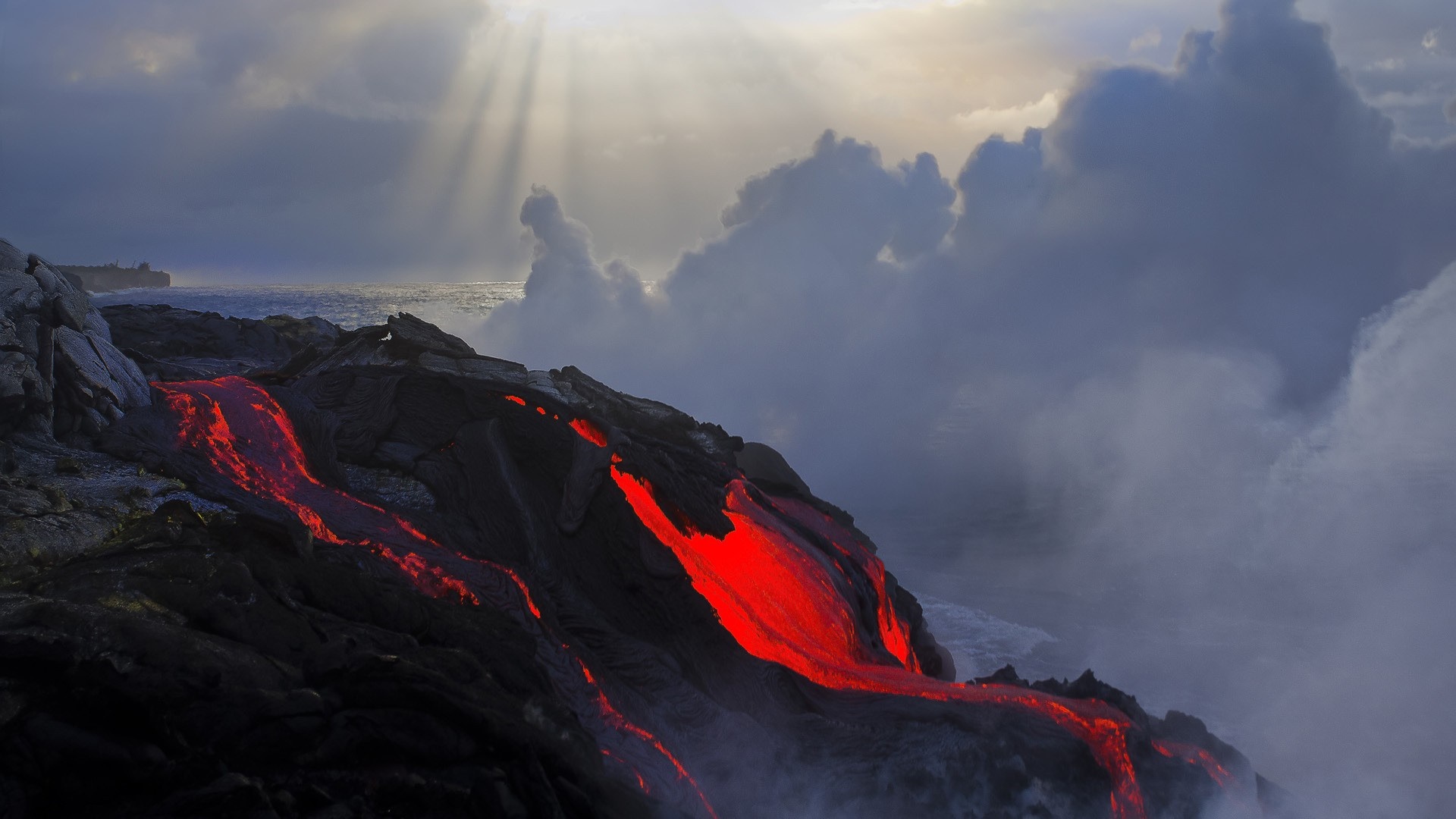 Molten lava flowing into the ocean under dramatic clouds HD Wallpaper
