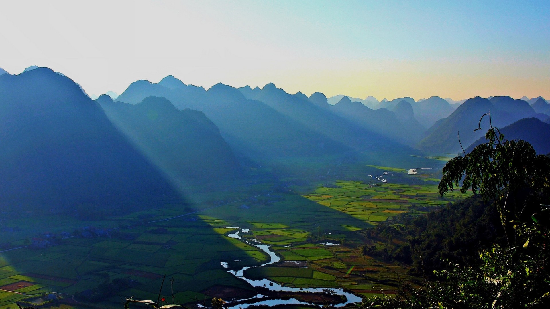 Sunlight streams through mountains over a valley in Vietnam HD Wallpaper