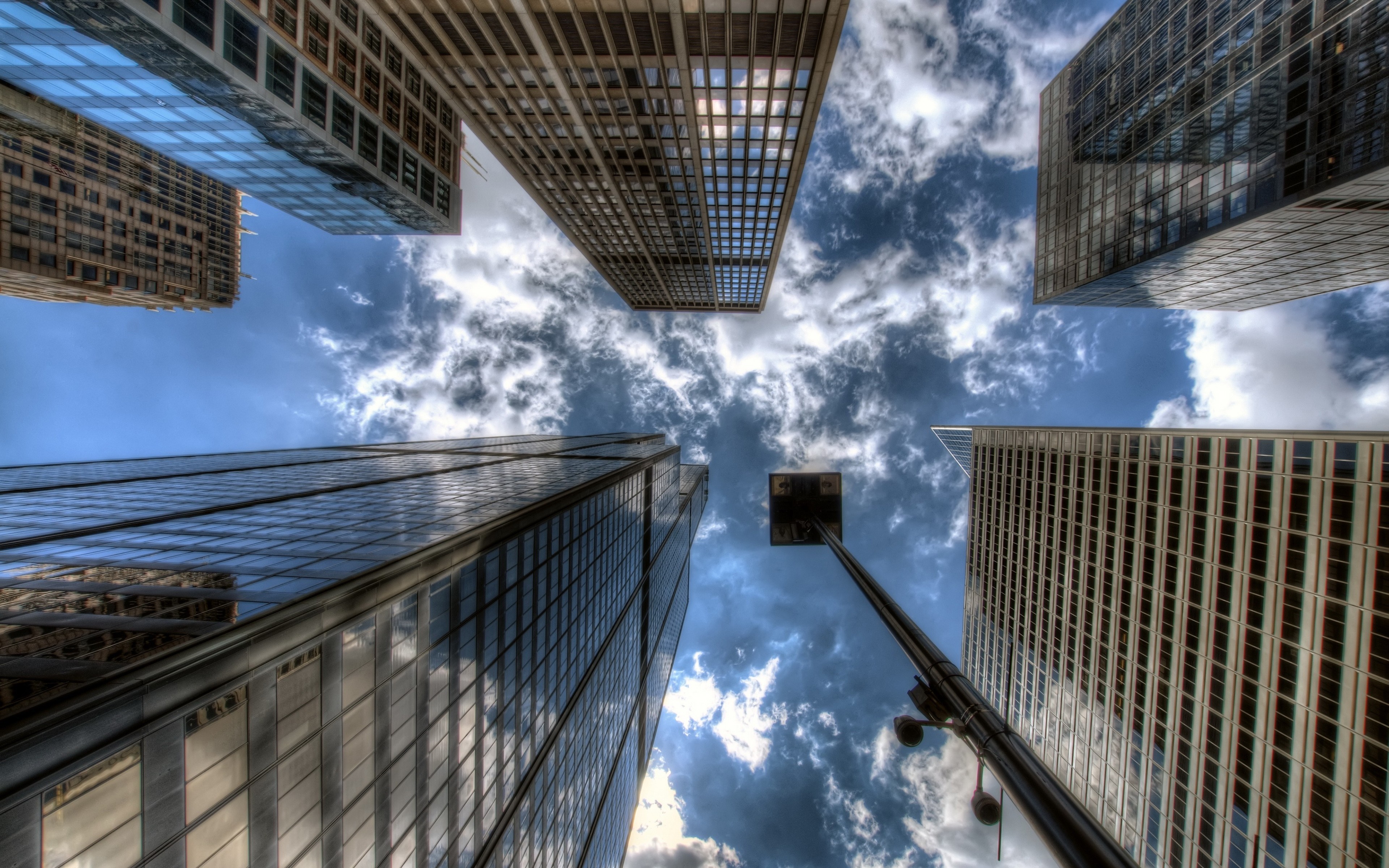 Looking up at skyscrapers against a cloudy sky HD Wallpaper