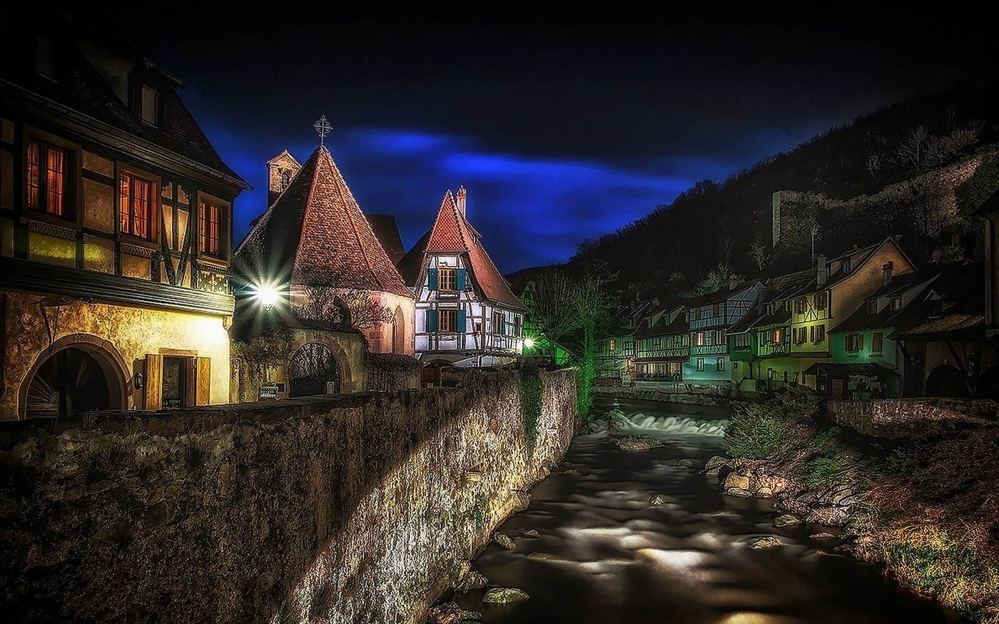 Night view of Kaysersberg village with a river and illuminated houses HD Wallpaper