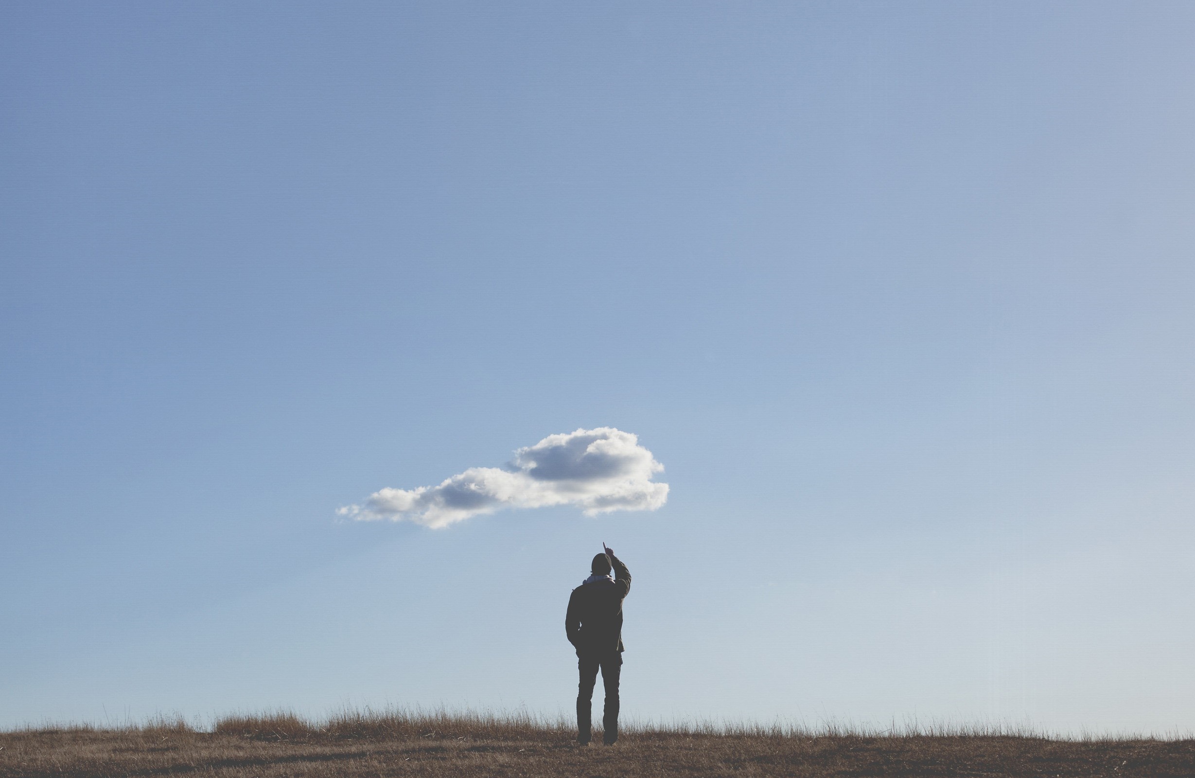 Man pointing at a cloud on a grassy hill HD Wallpaper