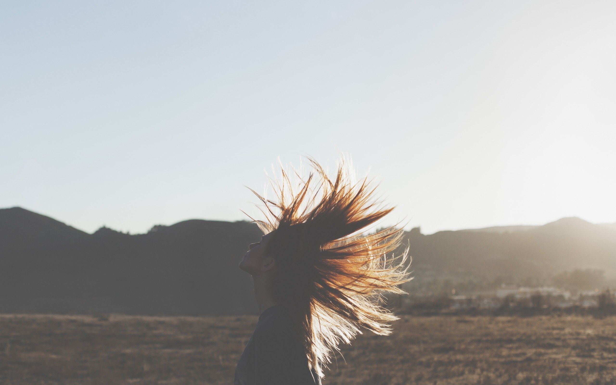 Woman with hair blowing in the wind at sunset HD Wallpaper