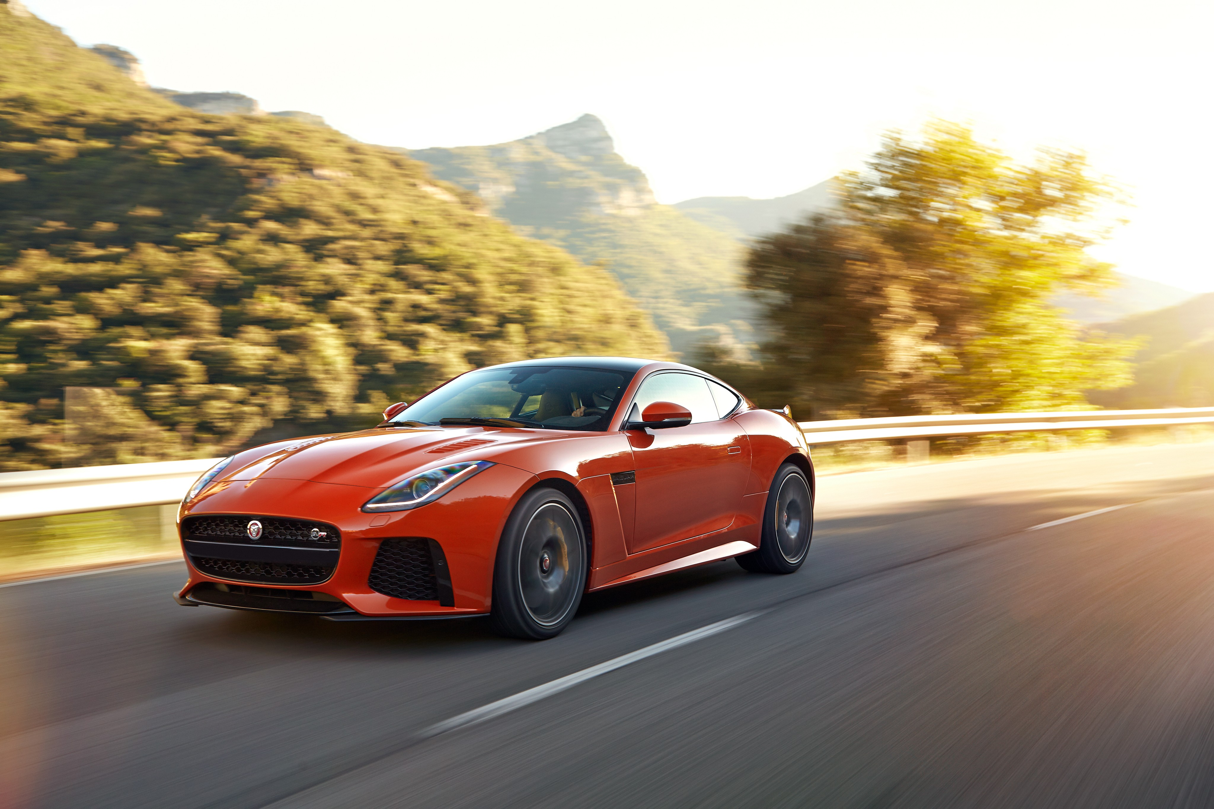 Orange Jaguar F-Type SVR driving on a mountain road HD Wallpaper