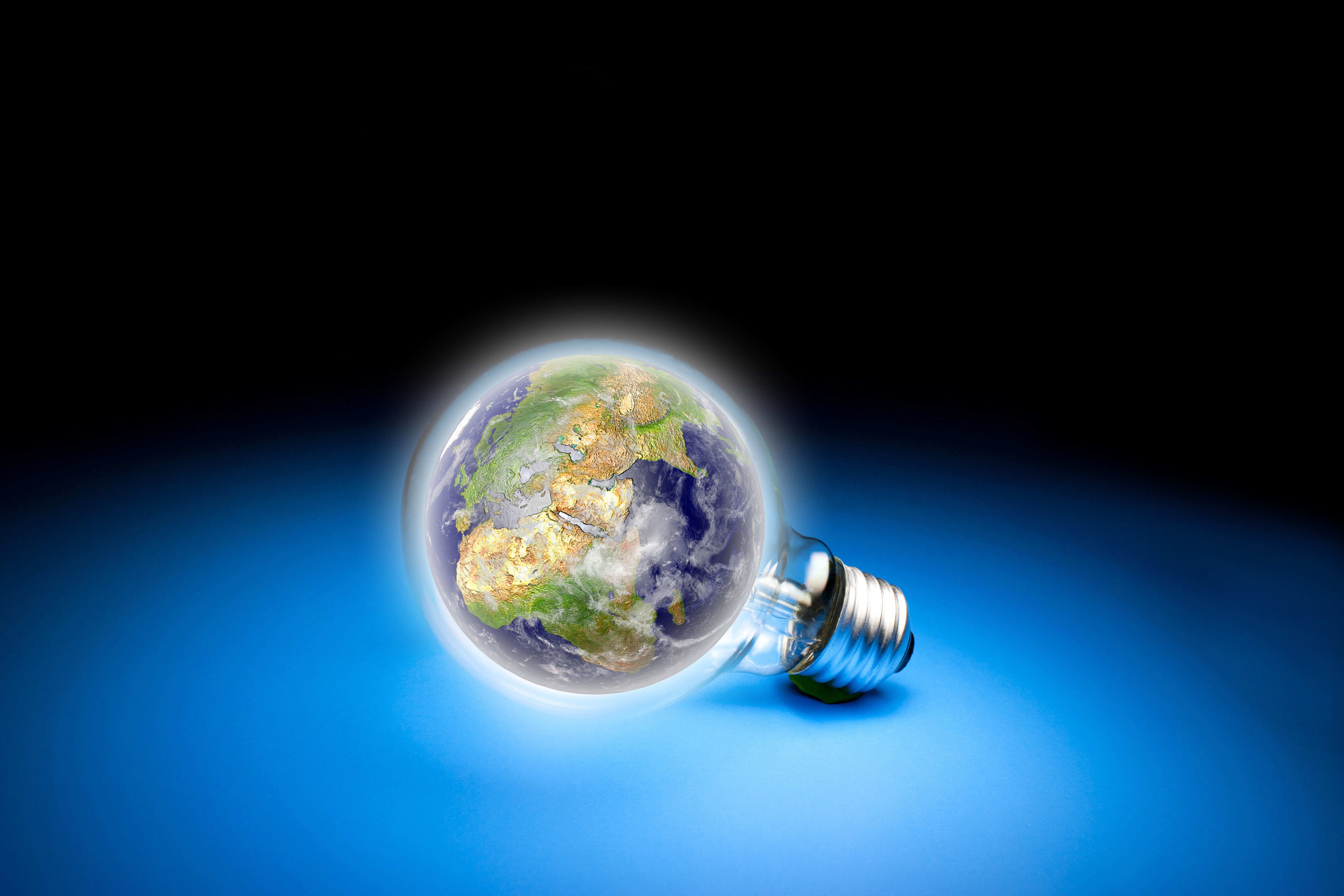 Earth inside a lightbulb on a blue surface HD Wallpaper
