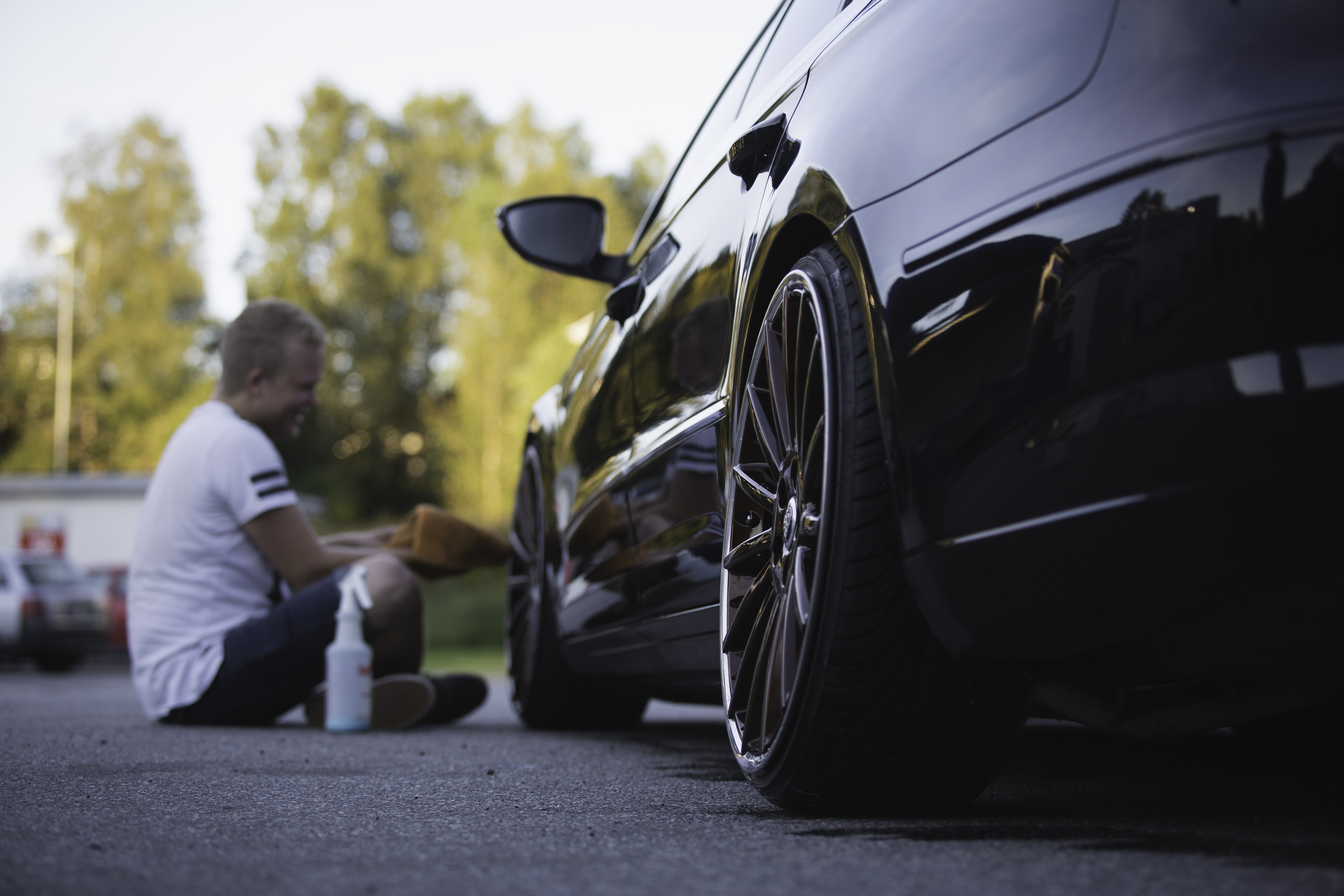 Man washing a black car with a spray bottle and cloth HD Wallpaper