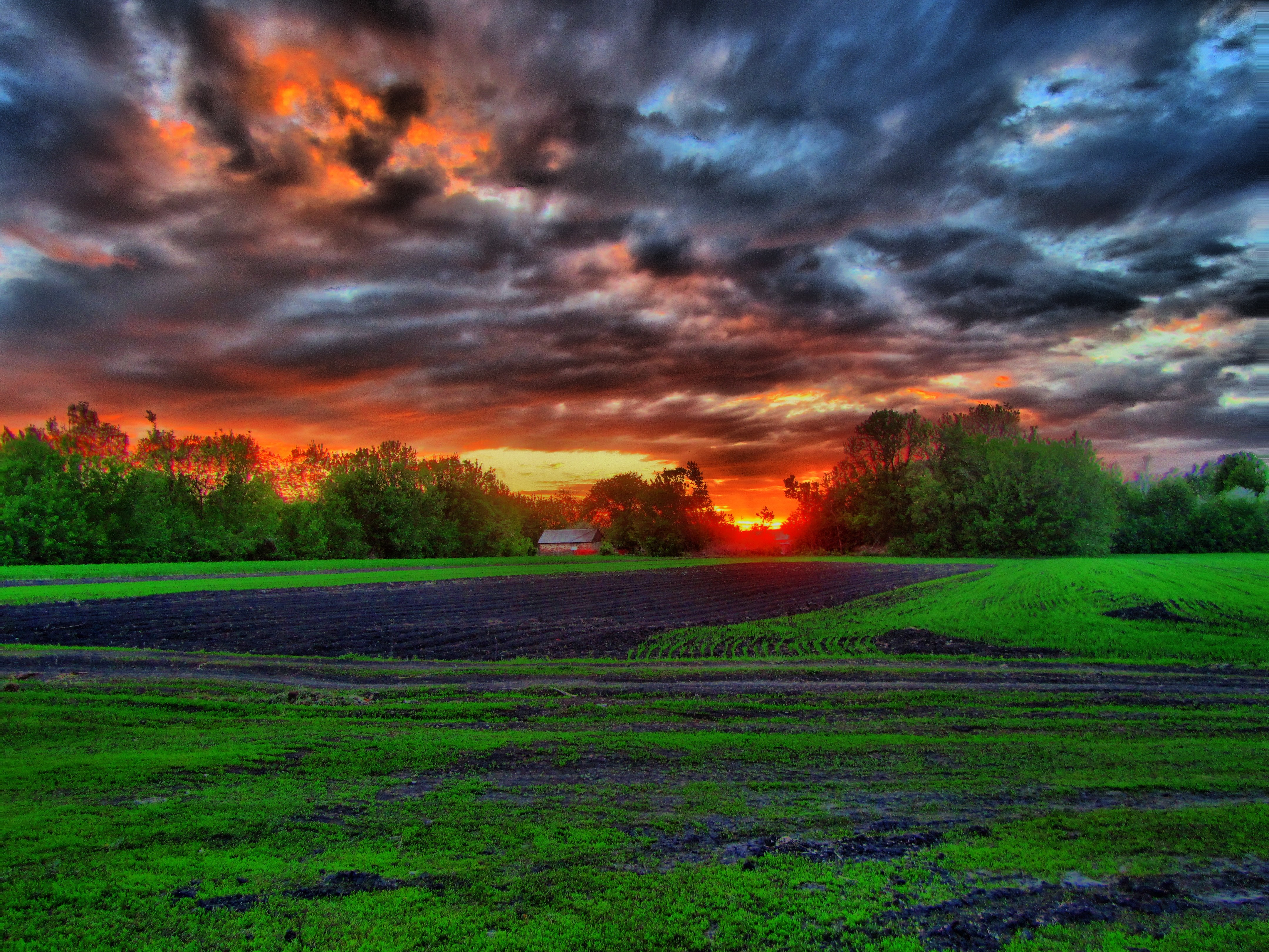 Sunset over a rural field with dramatic clouds HD Wallpaper