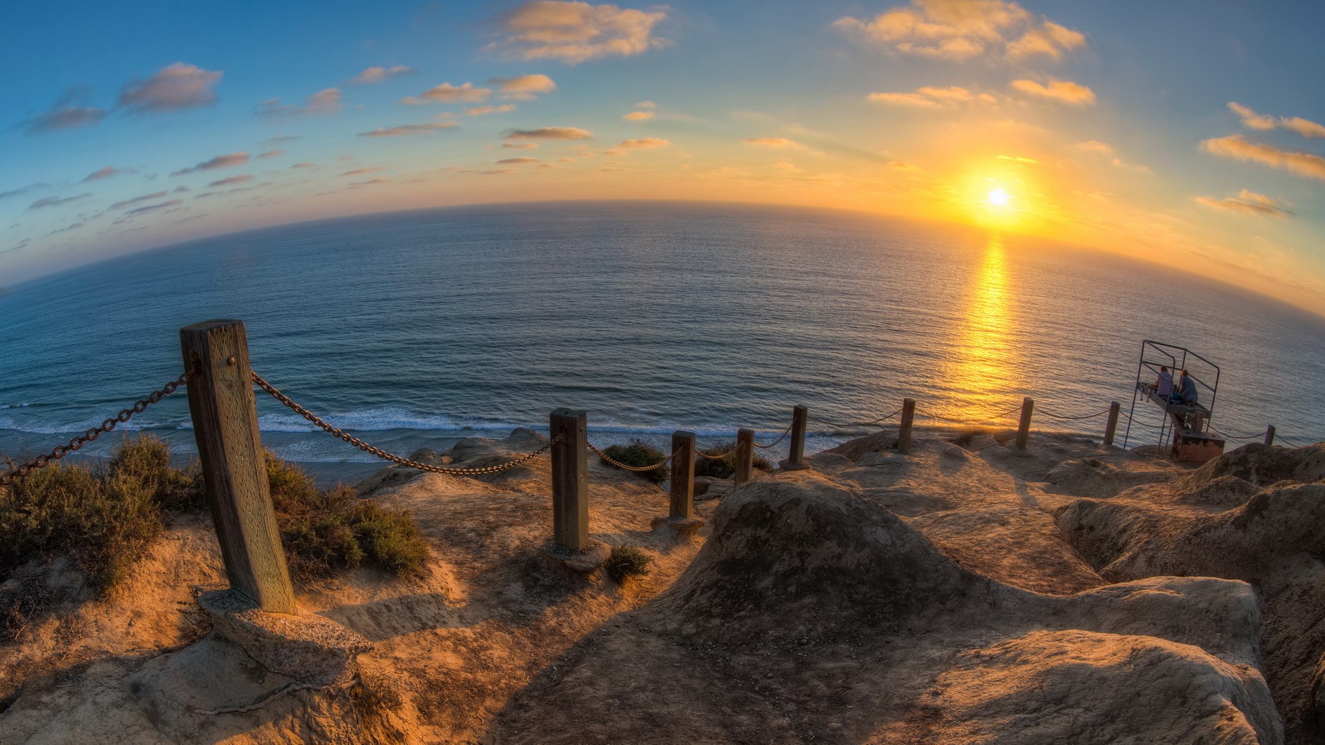 Sunset over the ocean with a cliffside path HD Wallpaper