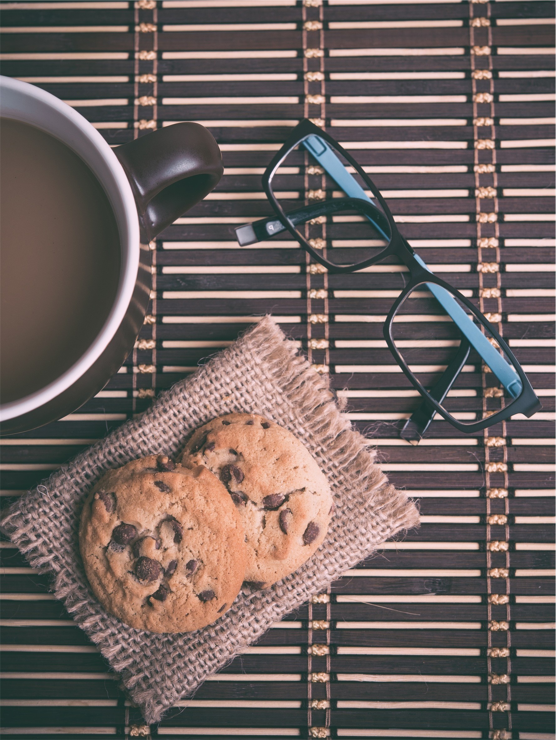 Coffee cup, cookies, and glasses on a bamboo mat HD Wallpaper